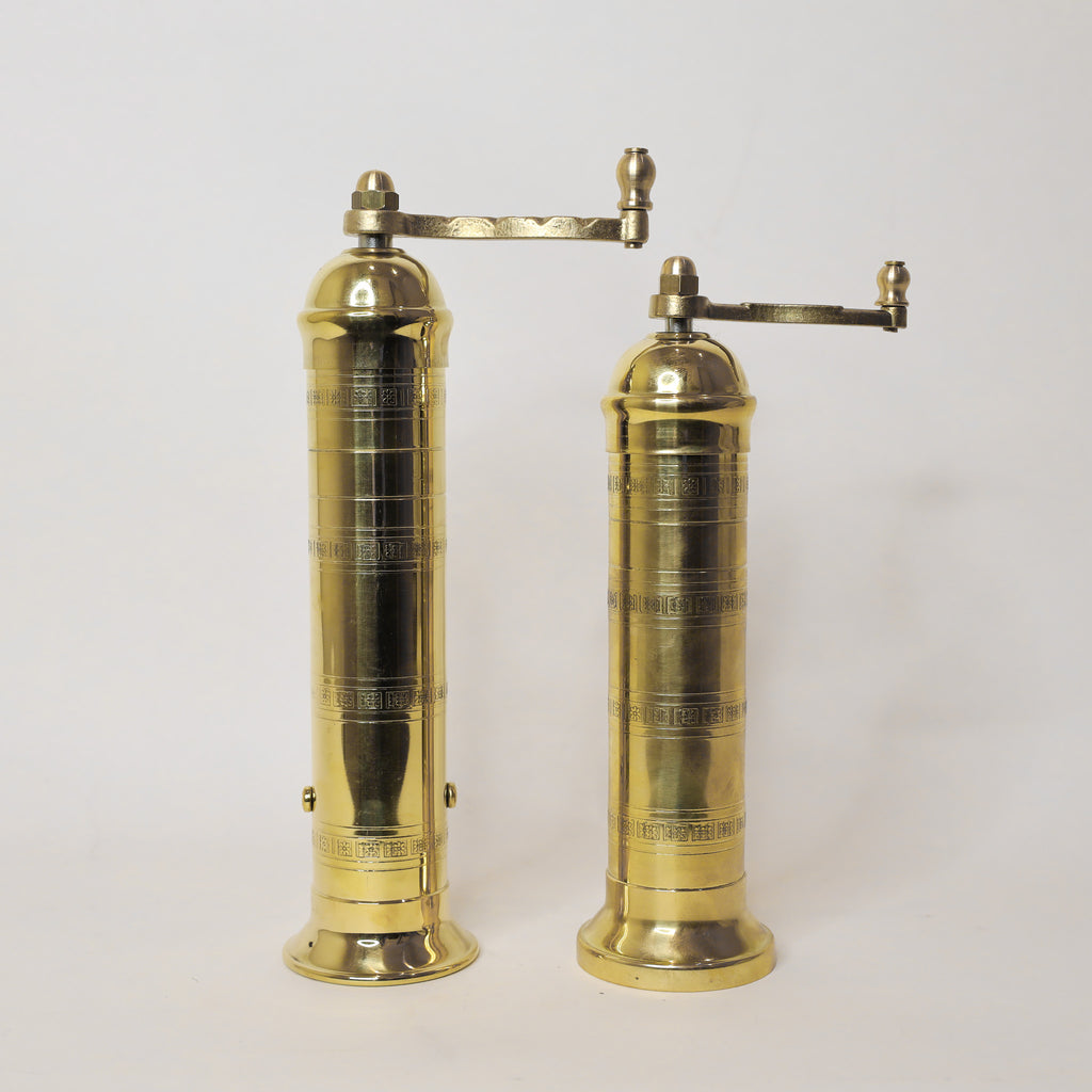 Pair of brass pepper mills on a white background