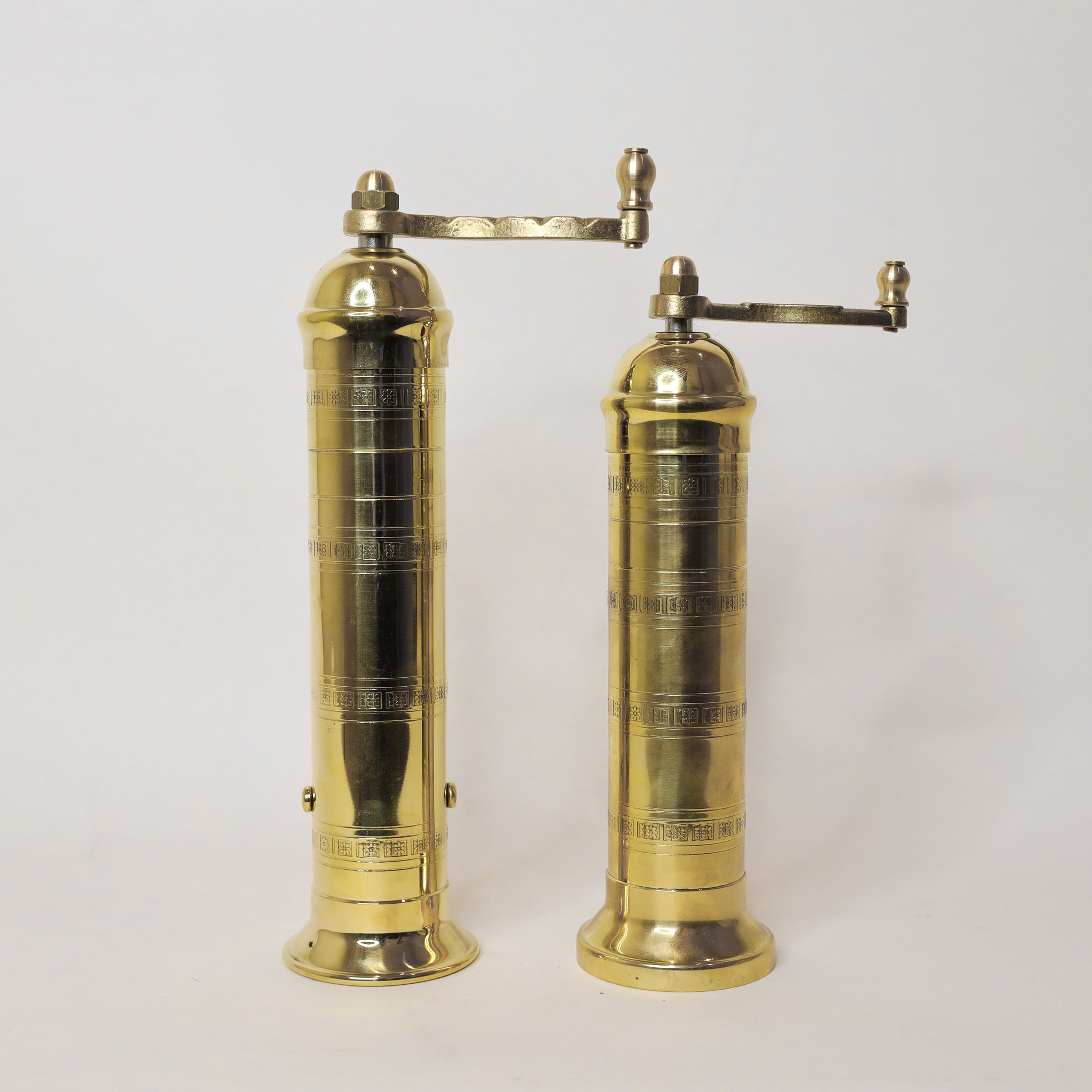Pair of brass pepper mills on a white background