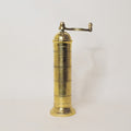 Brass pepper grinder on a light gray background