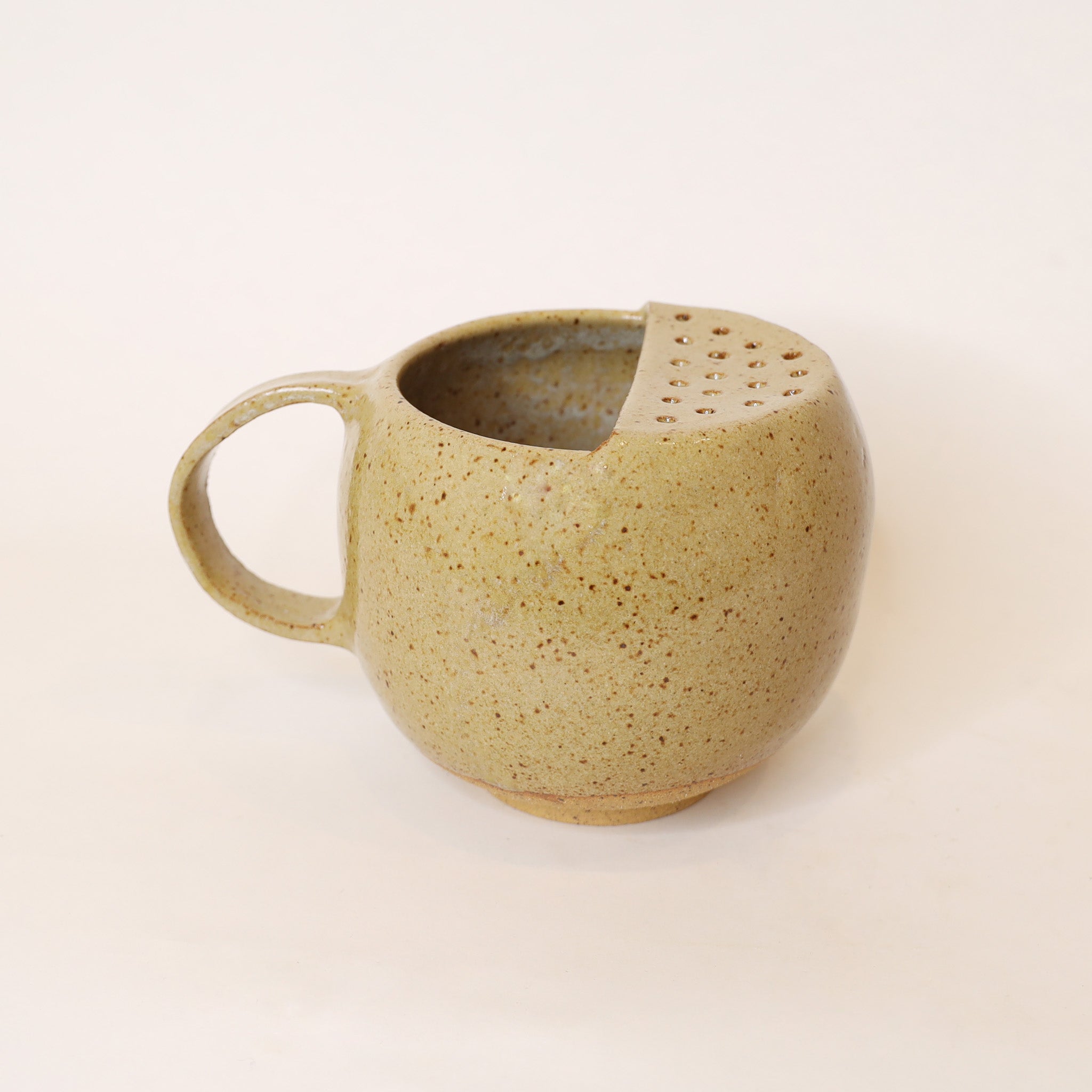 Speckled brown ceramic mug on a beige background