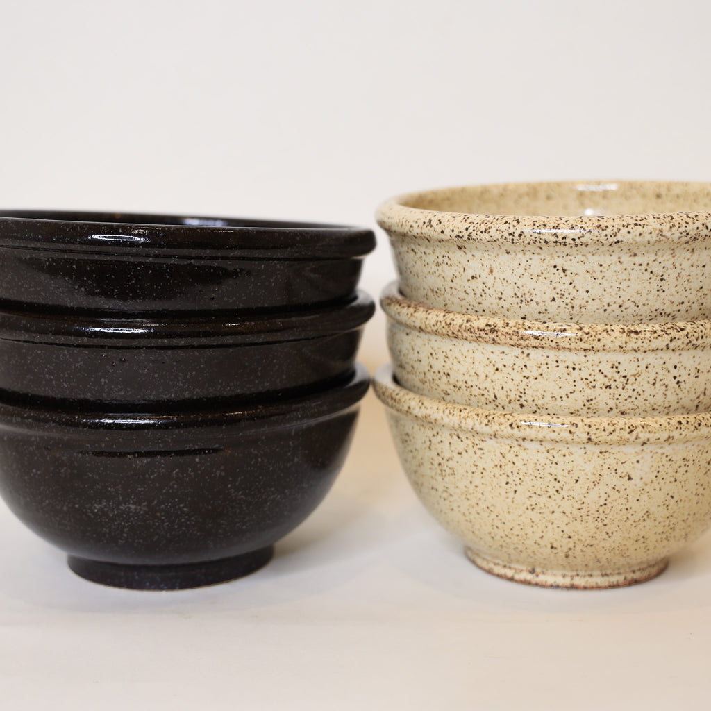 Set of black and beige ceramic bowls on a white background