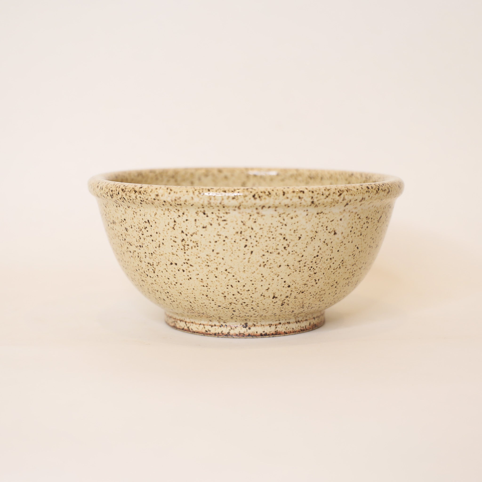 Speckled beige ceramic bowl on a light beige background
