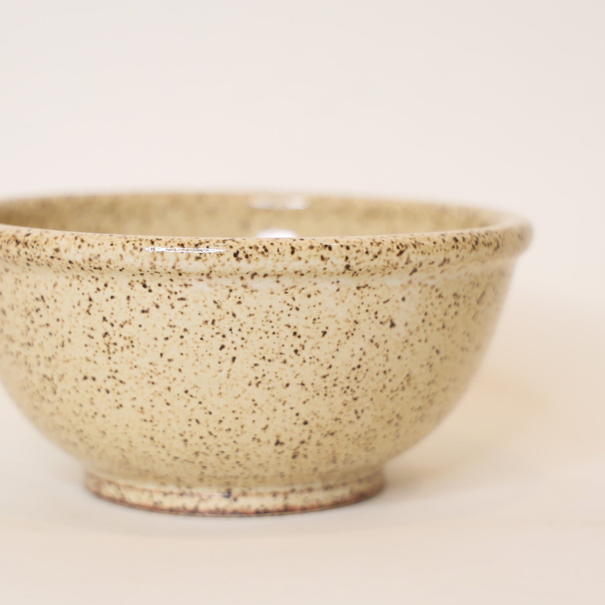 Speckled beige ceramic bowl on a light background