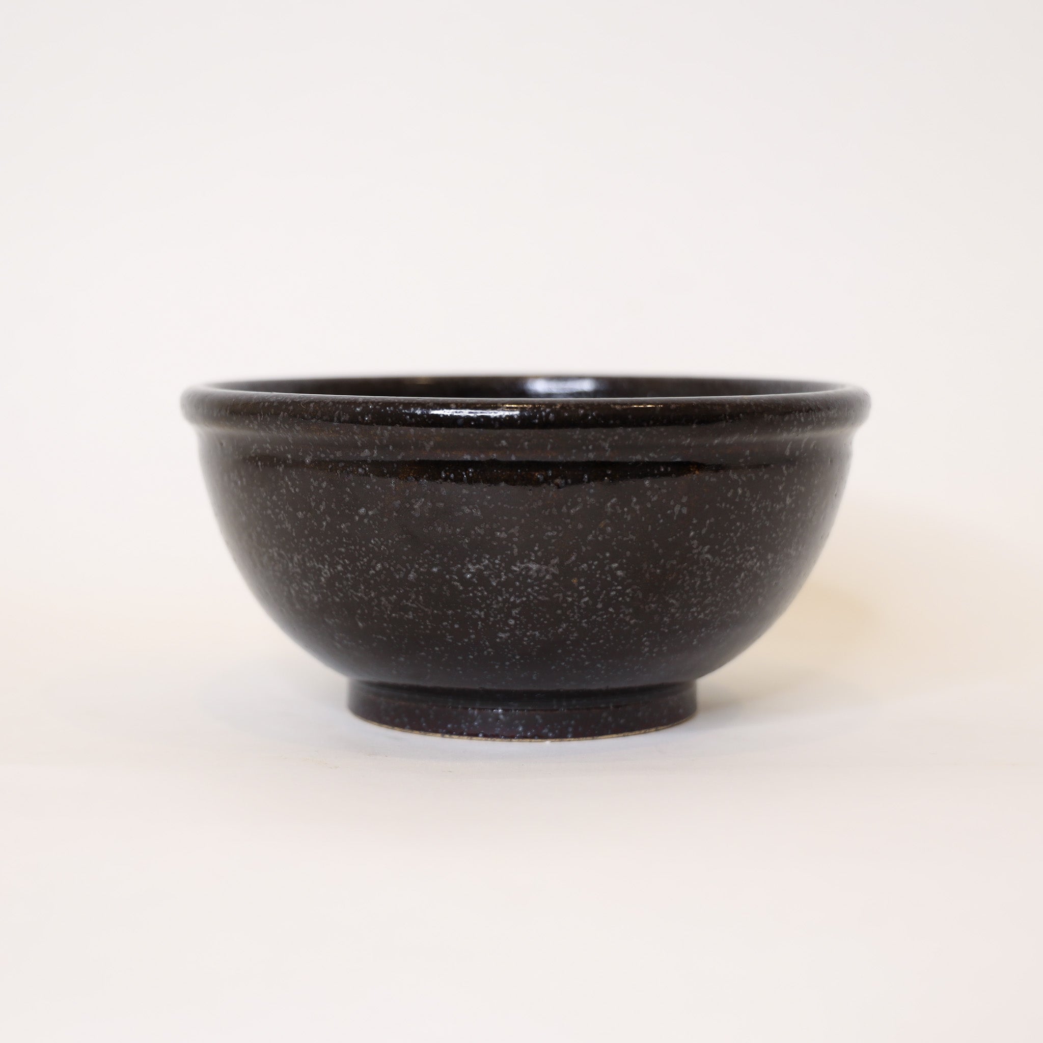 Black speckled ceramic bowl on a white background