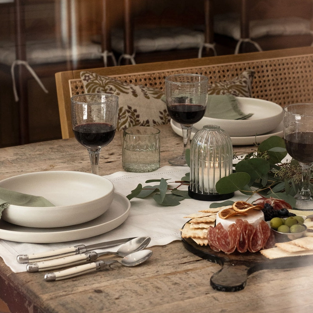 Elegant dining table set with plates, glasses, and a cheese board.