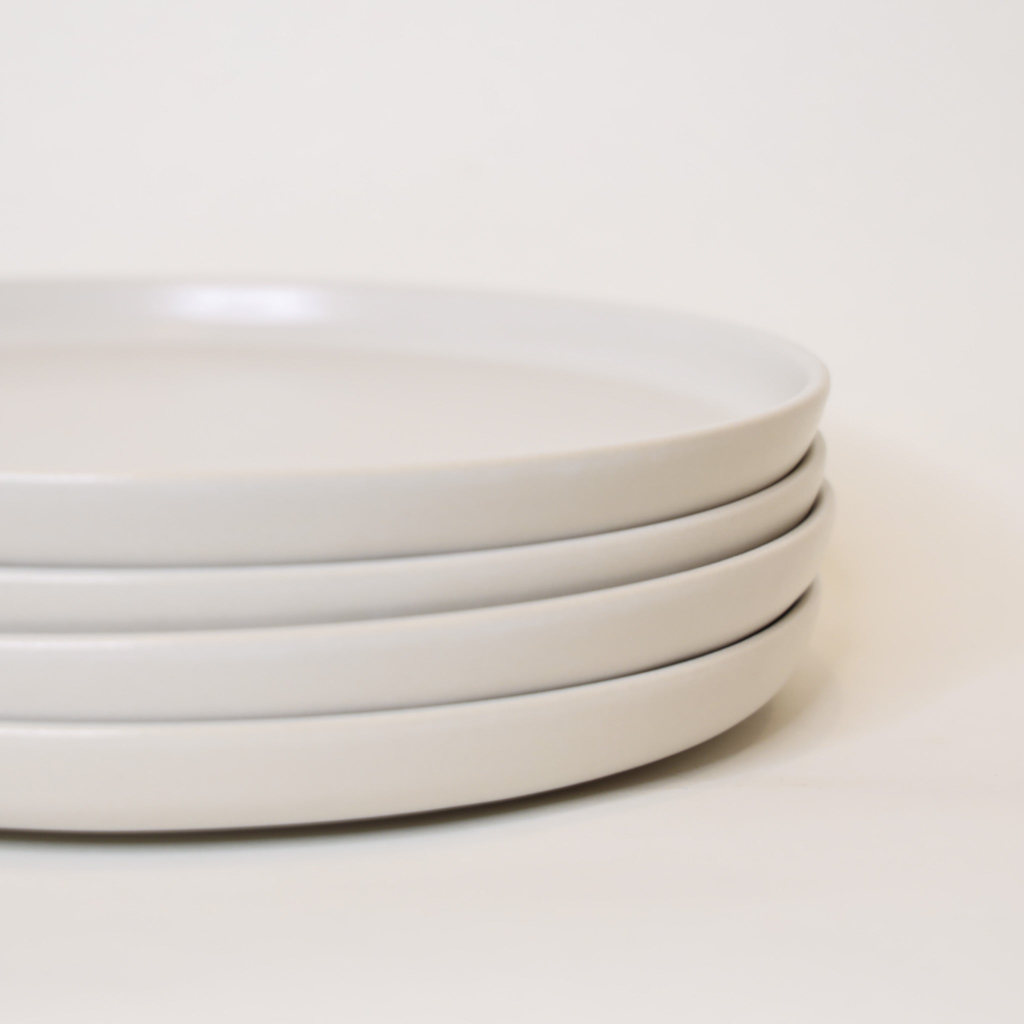 Stack of white ceramic plates on a light beige background