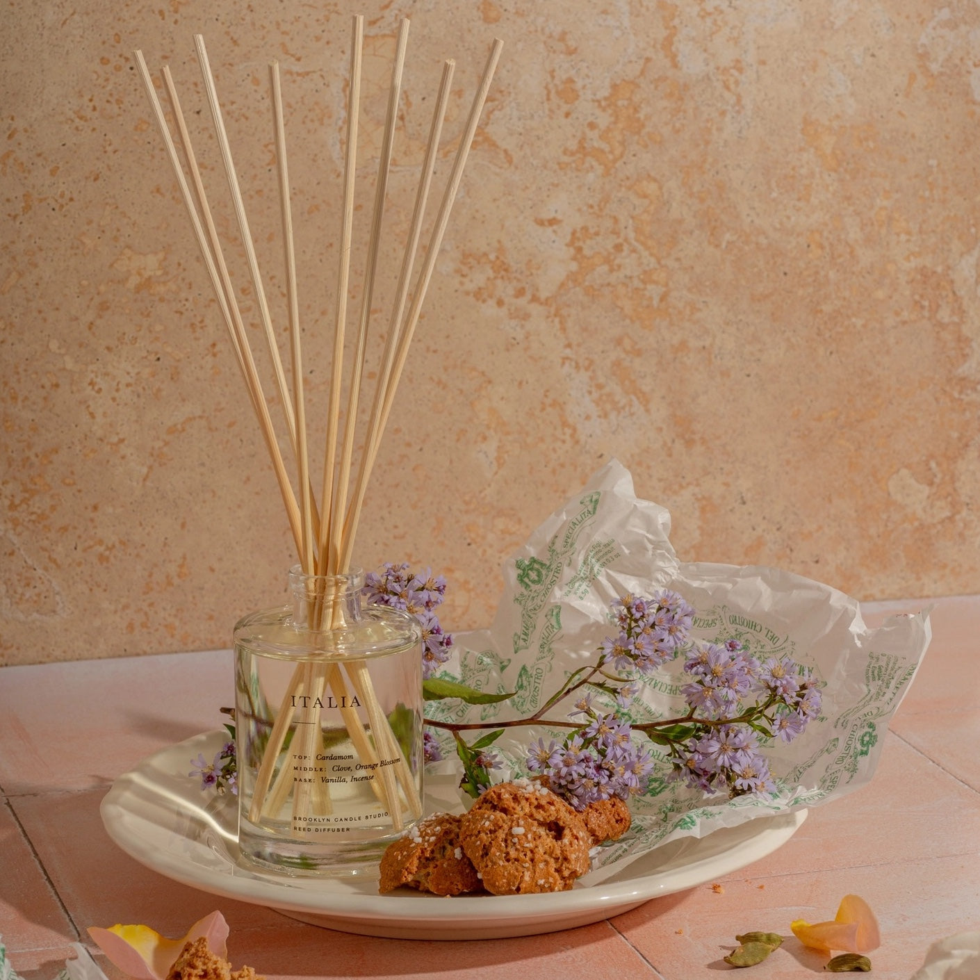 Reed diffuser with floral elements on a textured surface