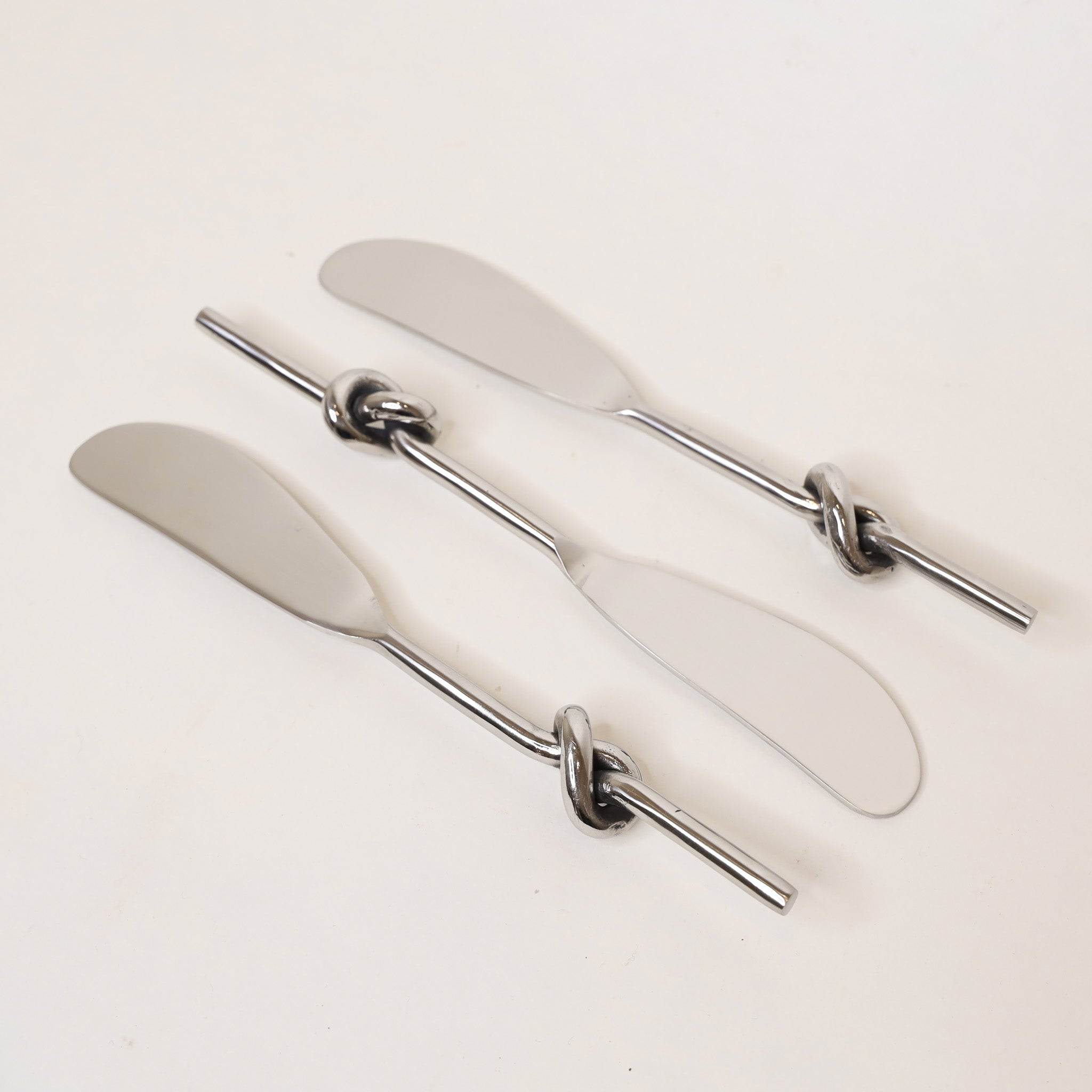 Set of three silver butter knives with decorative handles on a white background