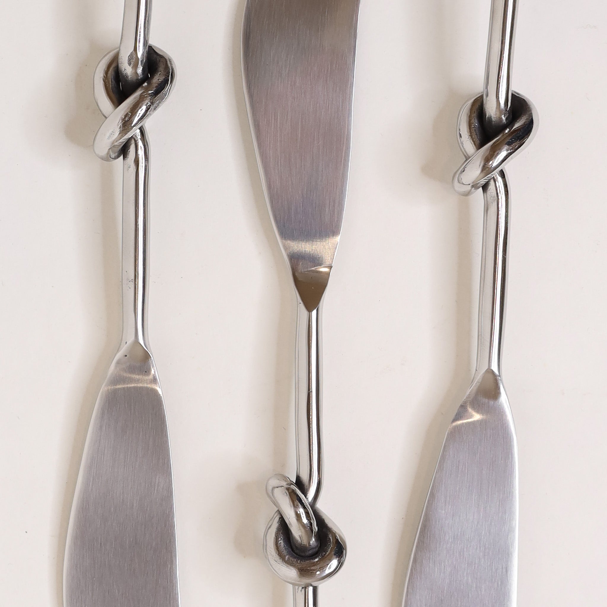 Three silver butter knives with decorative handles on a white background