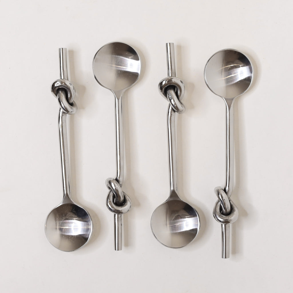Set of four metal spoons with knotted handles on a white background