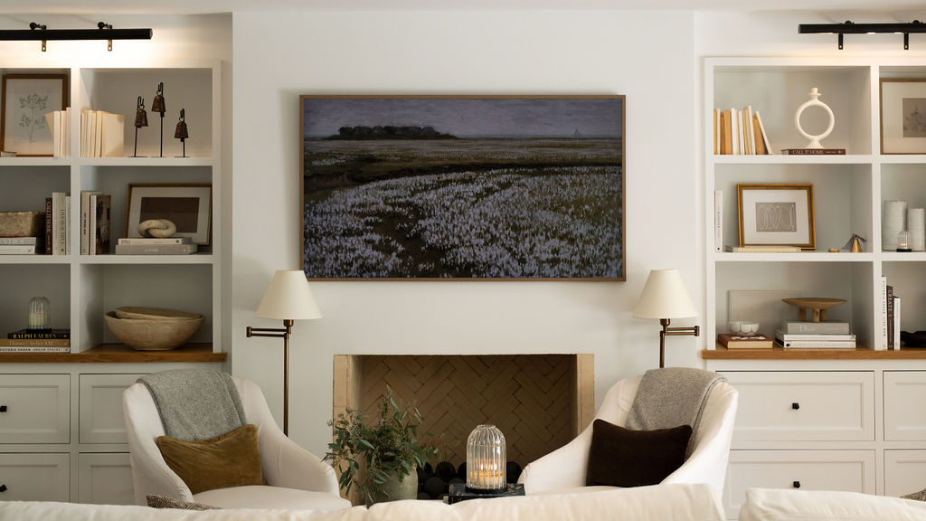 Living room with white walls, a fireplace, and bookshelves.