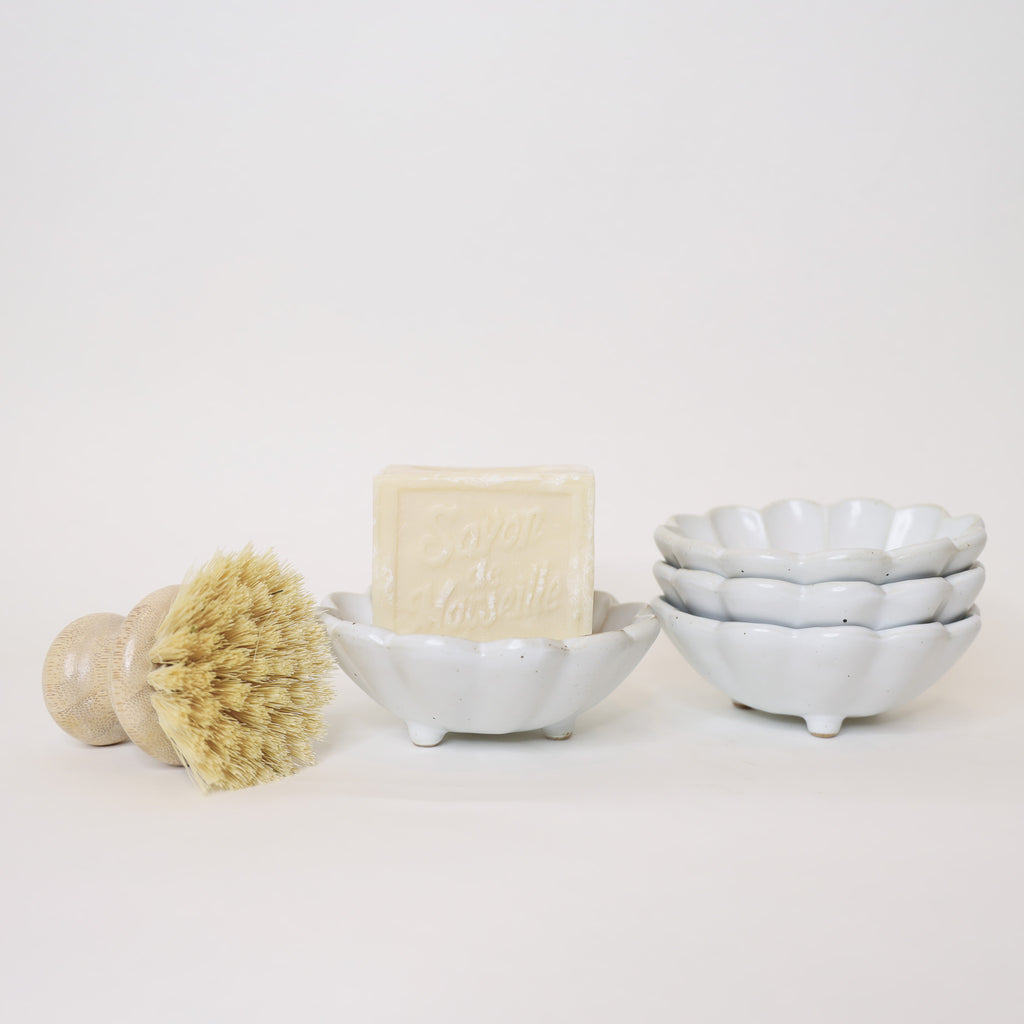 Bar of soap, brush, and ceramic bowls on a white background