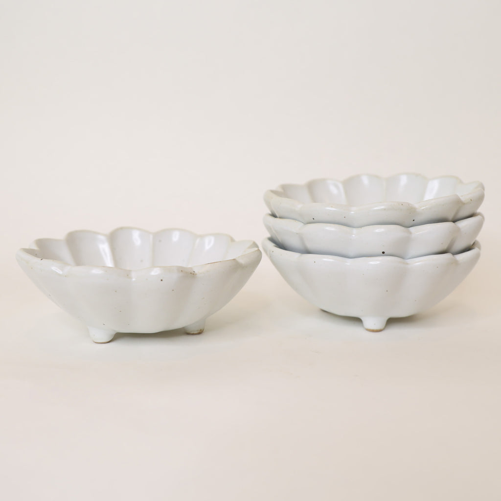 Set of three white ceramic bowls with textured edges on a light background