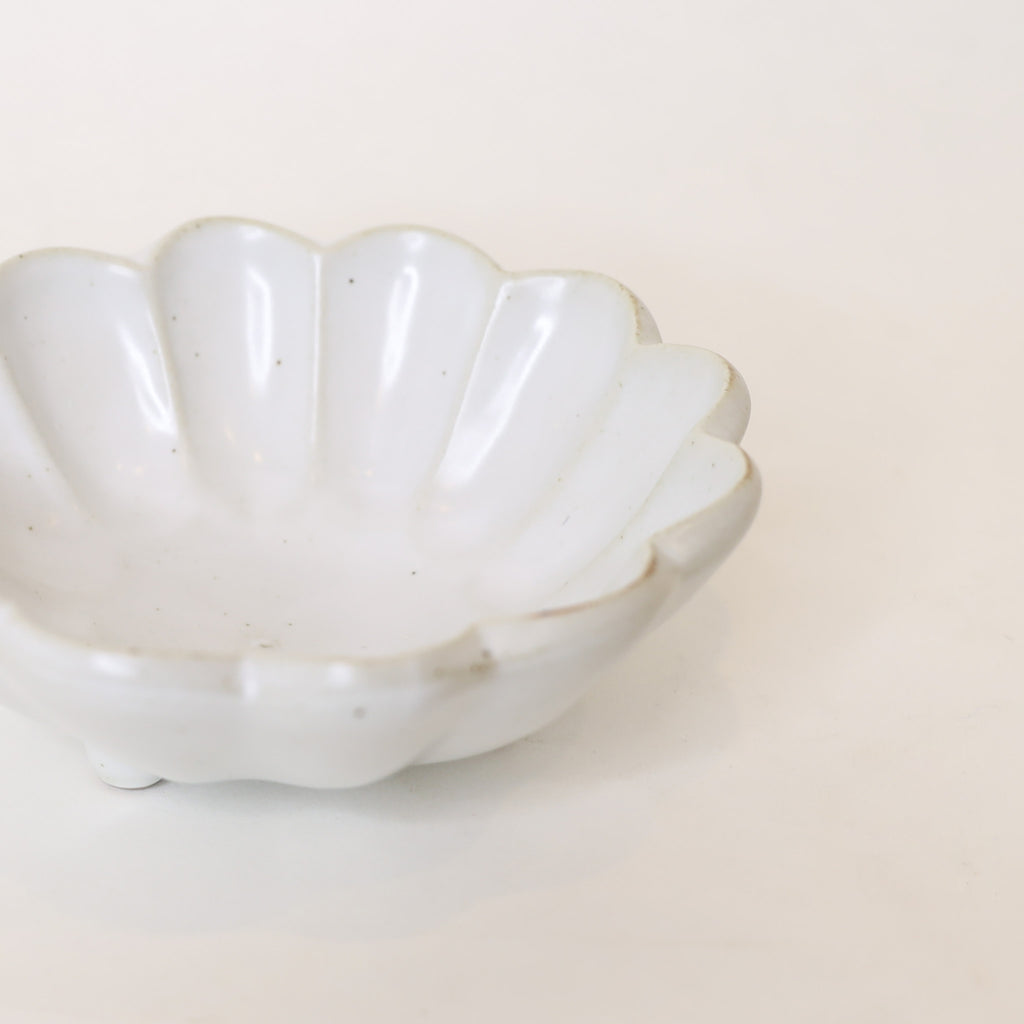 White ceramic bowl with scalloped edge on a light beige background