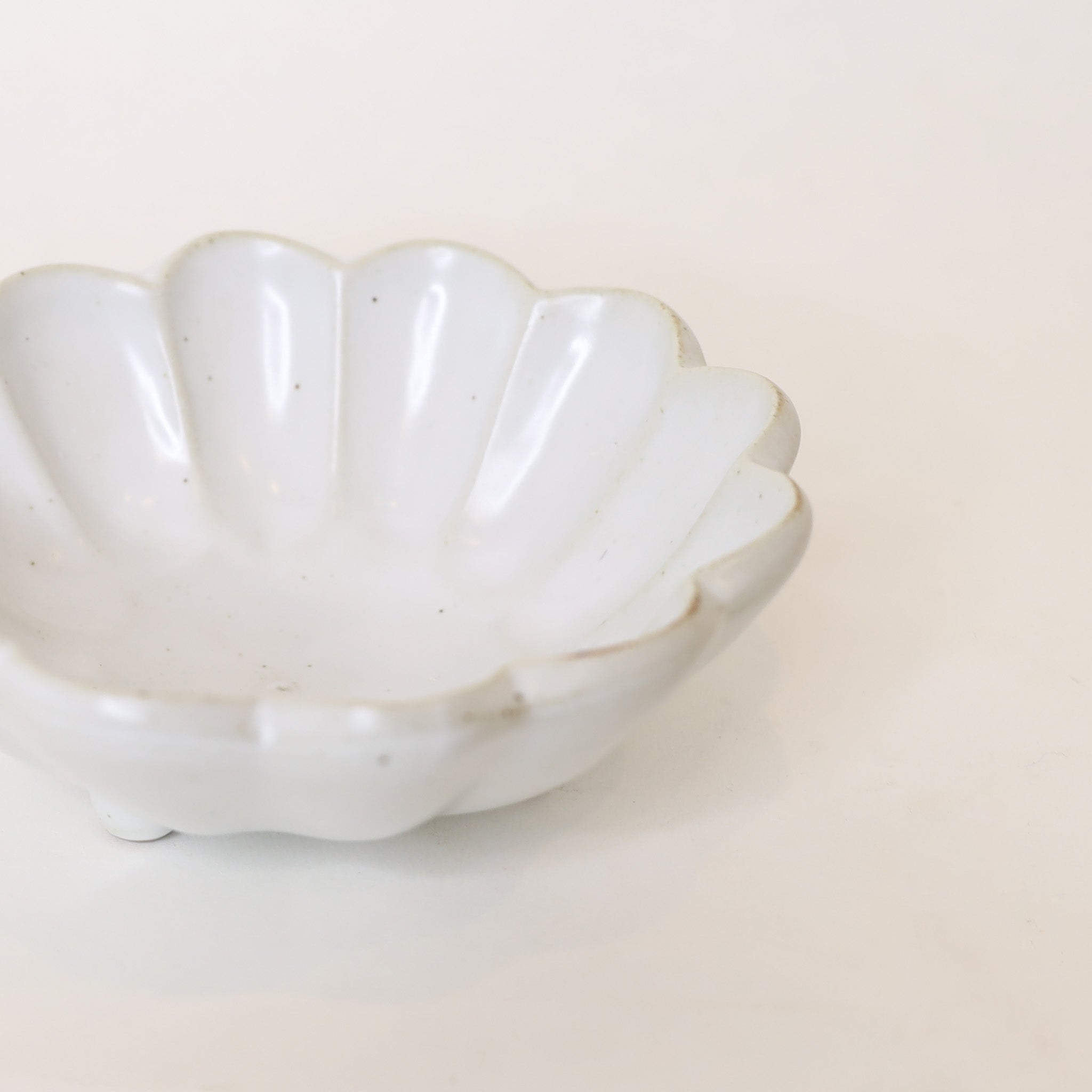 White ceramic bowl with scalloped edge on a light beige background