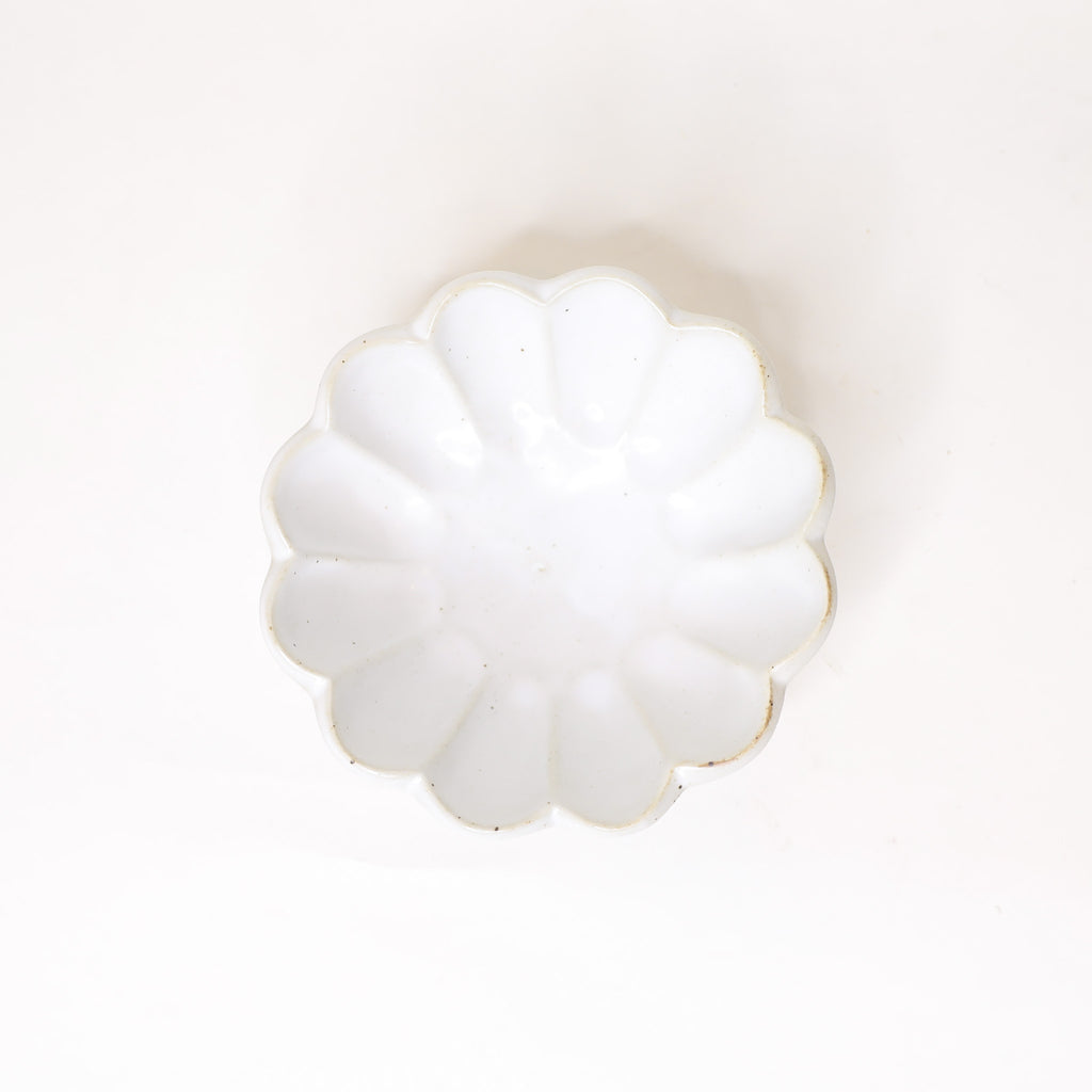 White decorative bowl with scalloped edges on a white background