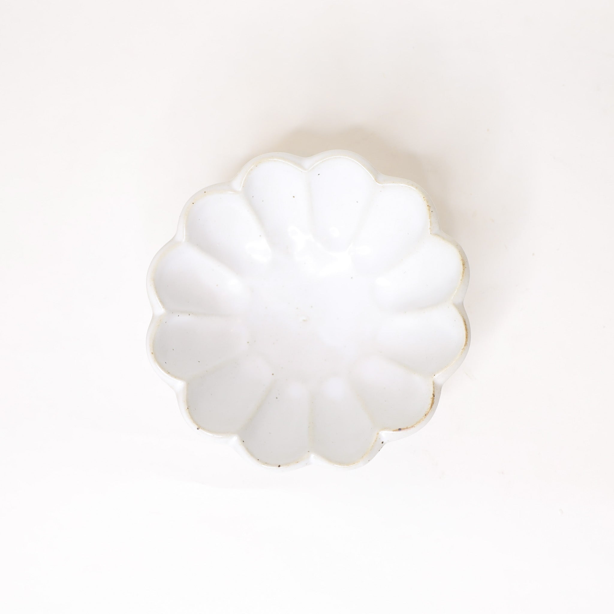 White decorative bowl with scalloped edges on a white background