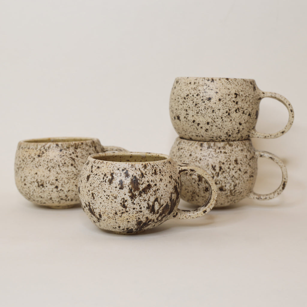 Set of speckled ceramic mugs on a plain background