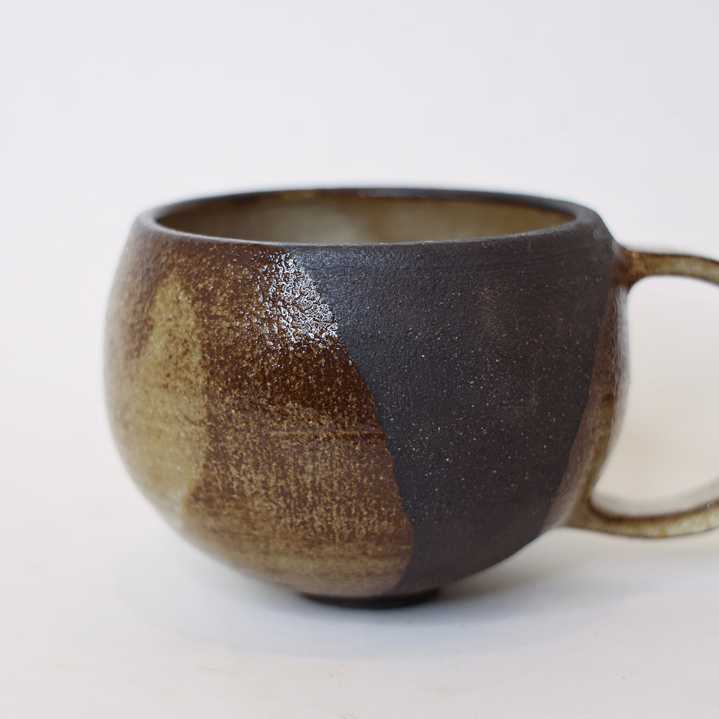 Ceramic mug with brown and black glaze on a white background