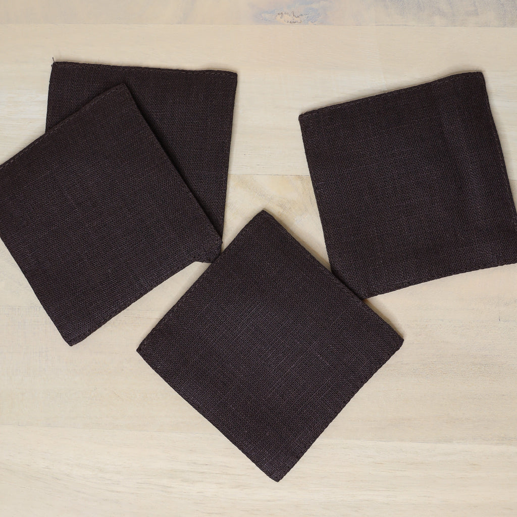 Four dark brown fabric squares on a light wooden surface