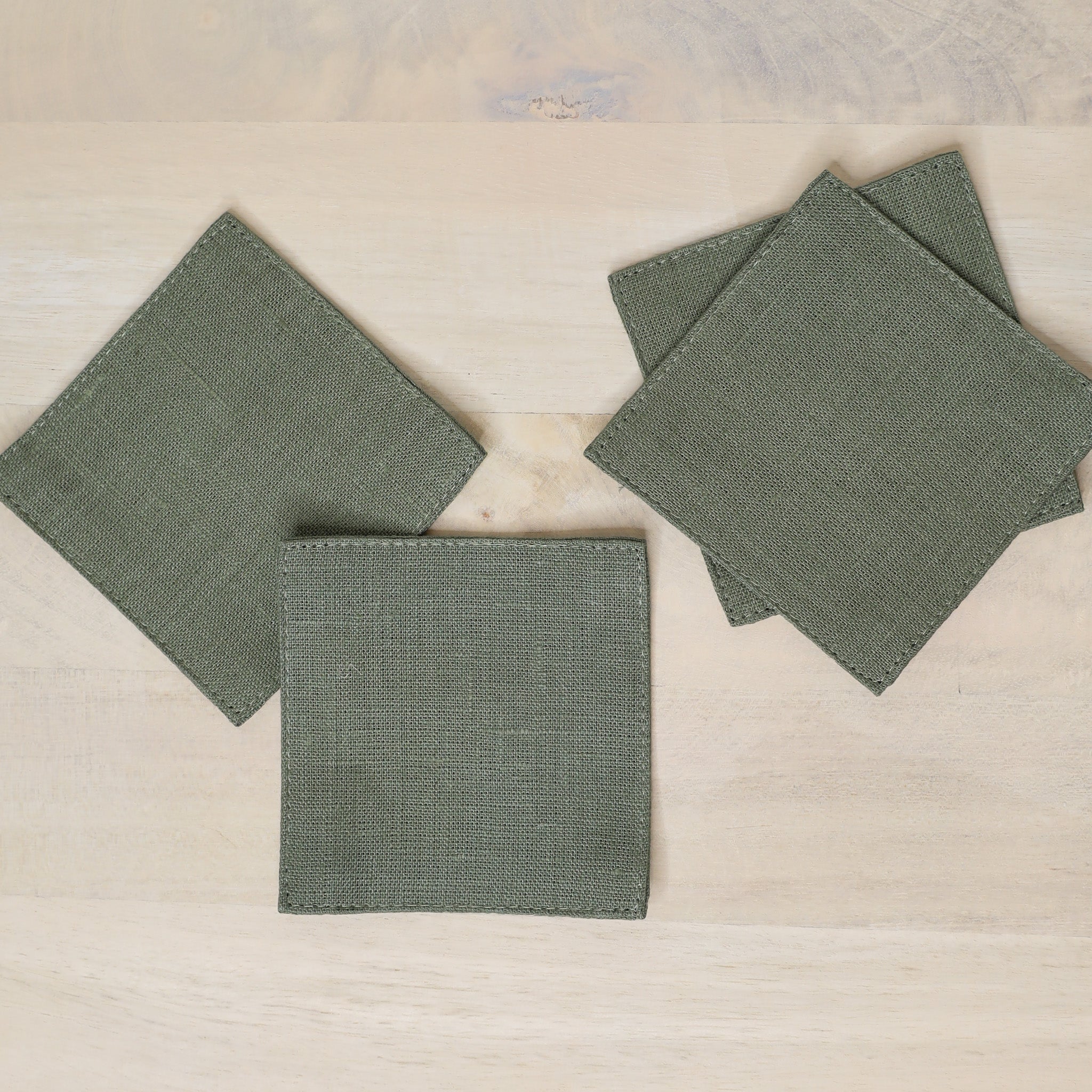Set of green fabric coasters on a beige surface