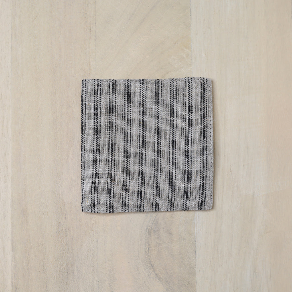 Textured square mat with black stripes on a light wood surface