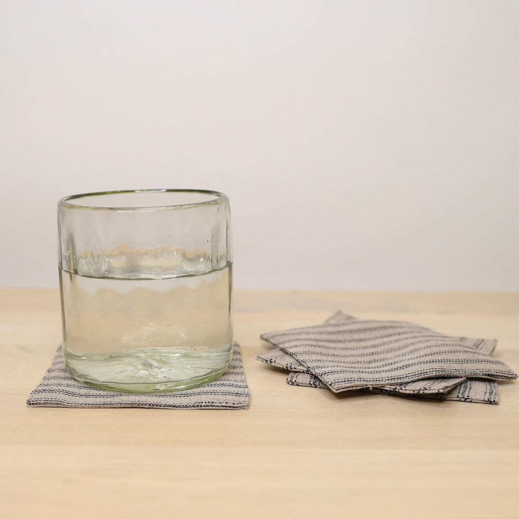 Clear glass with water on a textured napkin on a beige surface