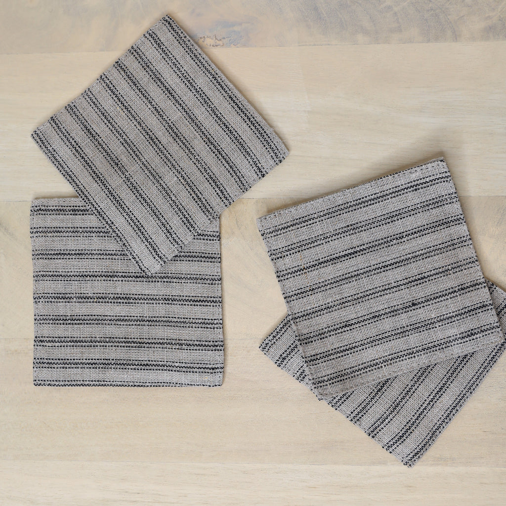 Set of four gray striped coasters on a wooden surface