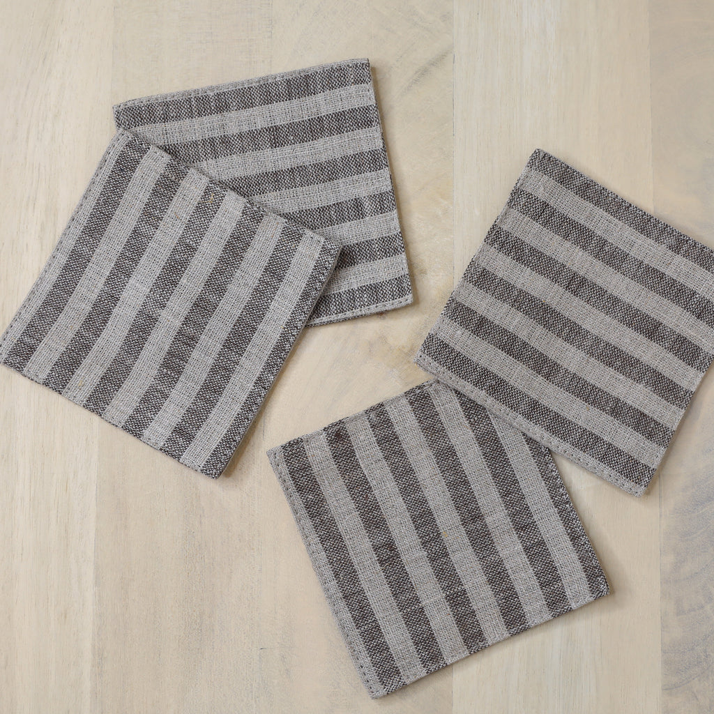 Four gray and white striped coasters on a wooden surface