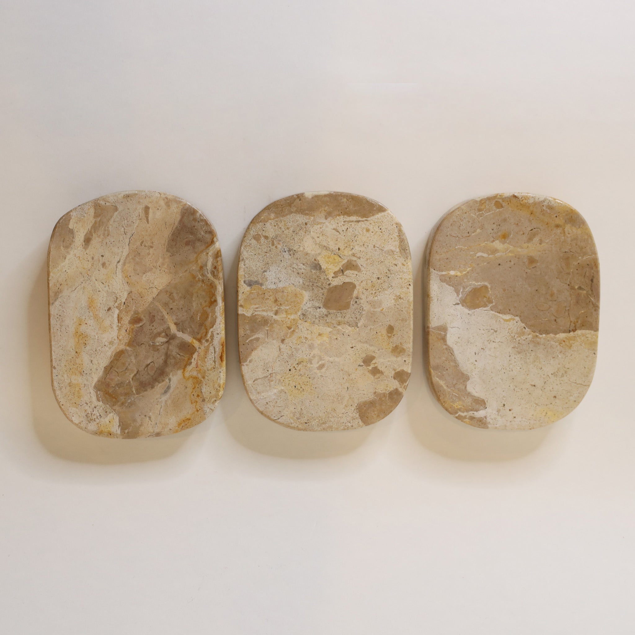 Three oval-shaped stone dishes with varying patterns on a white background