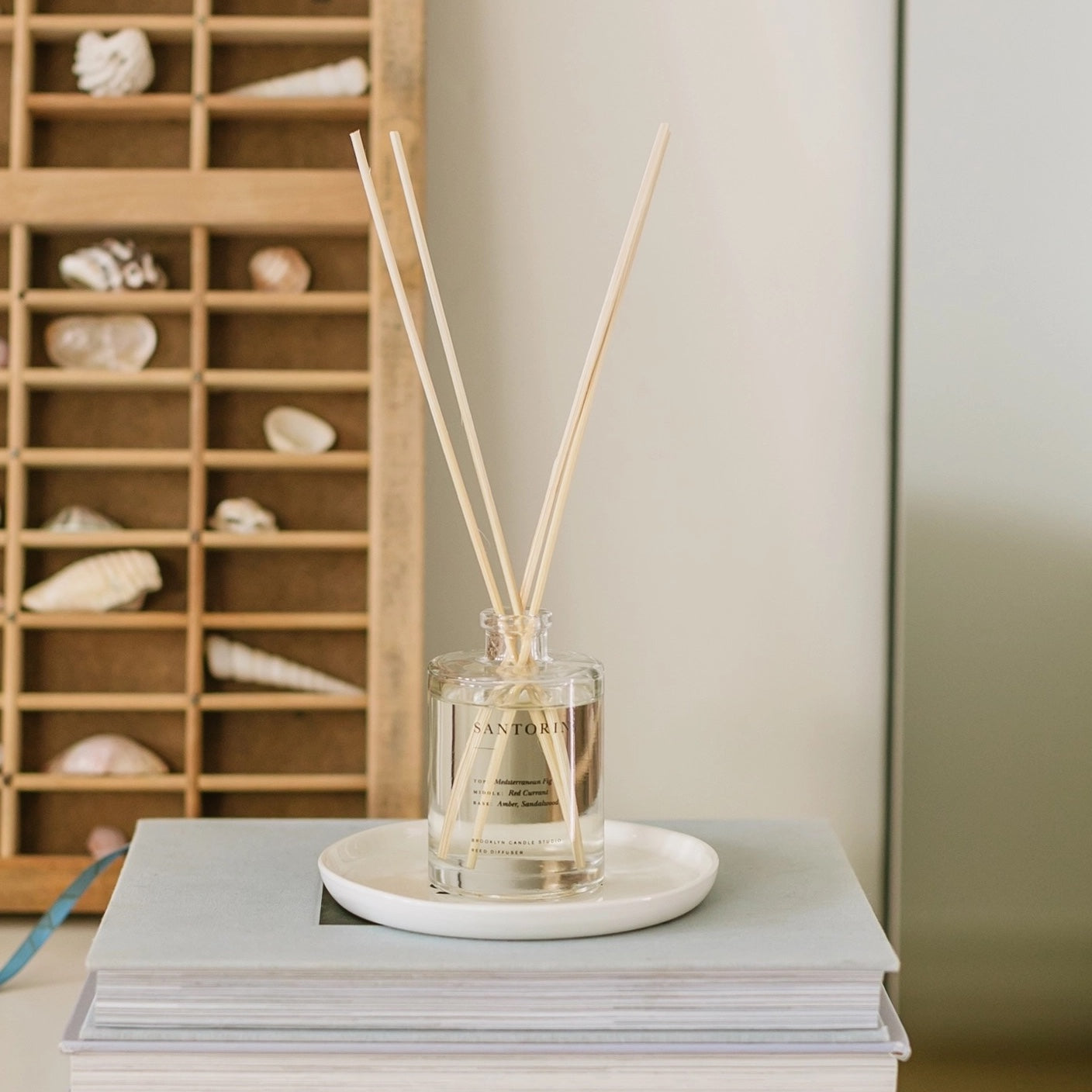 Reed diffuser on a stack of books with a wooden shelf in the background