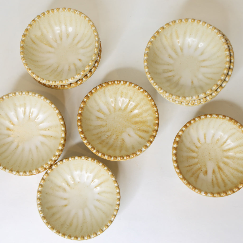 Set of six ceramic bowls with gold rims on a white background