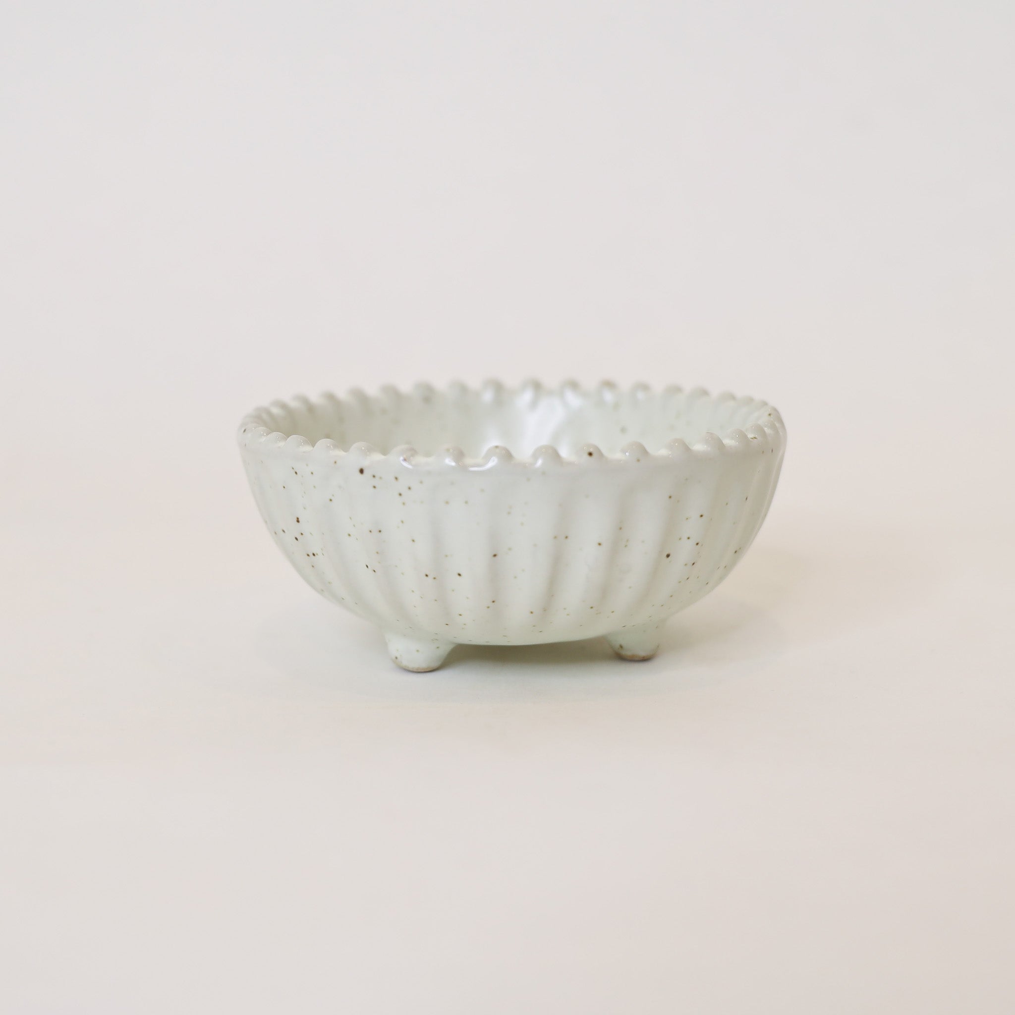 White ceramic bowl with textured surface on a light beige background