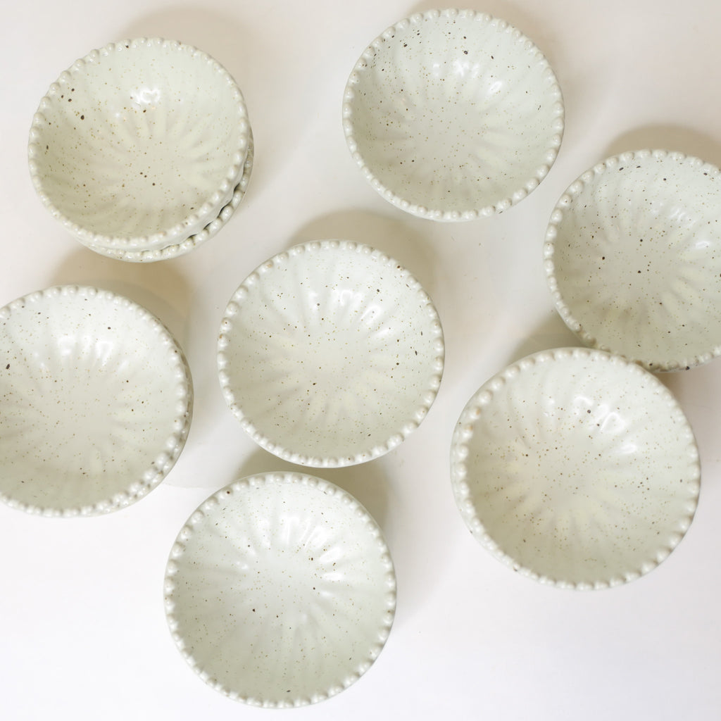 Set of ceramic bowls with speckled texture on a light background