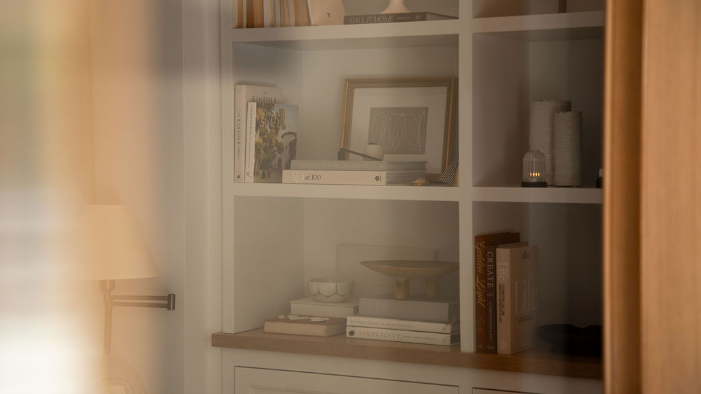 Wooden bookshelf with books and decorative items in a softly lit room