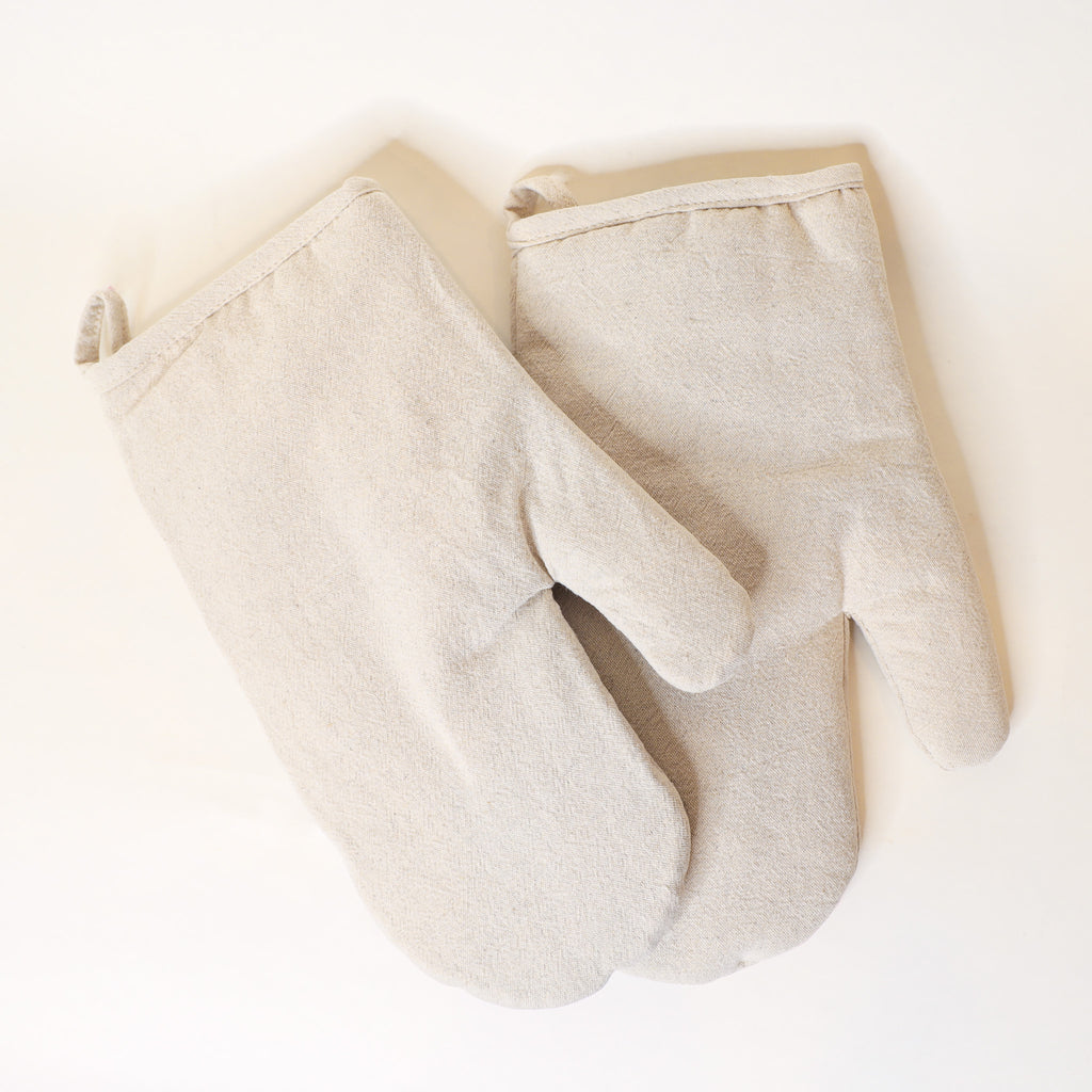 Pair of beige oven mitts on a white background