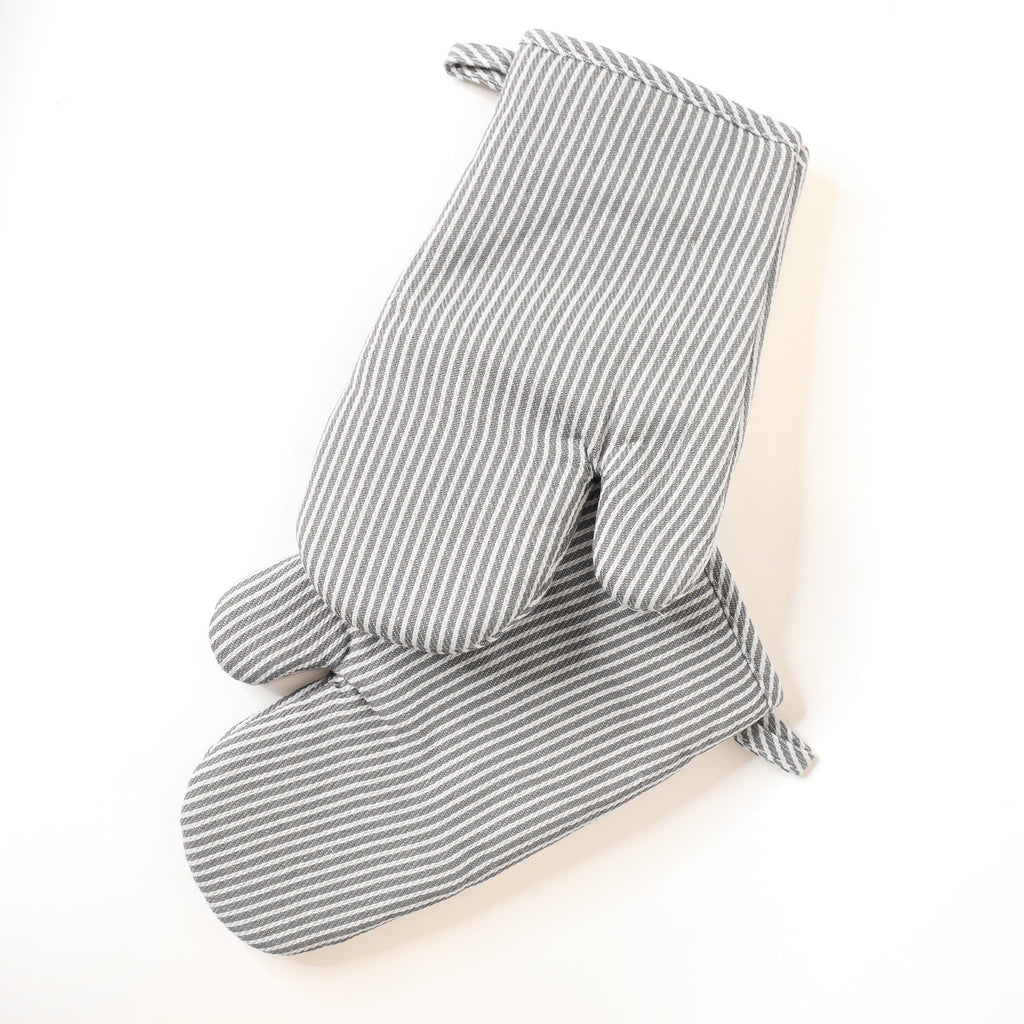 Pair of gray and white striped oven mitts on a light beige background