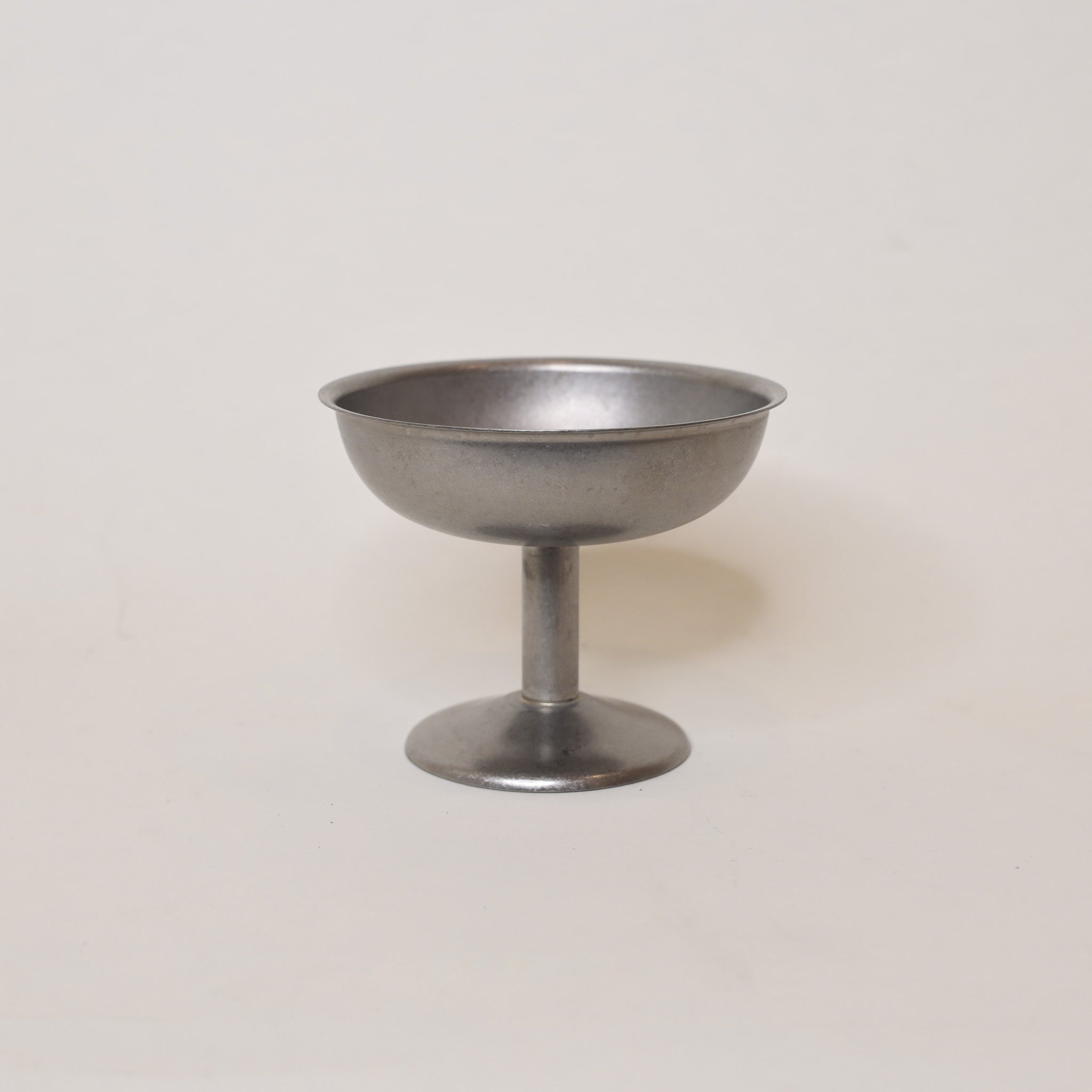 Silver metal coupe cup on a light beige background