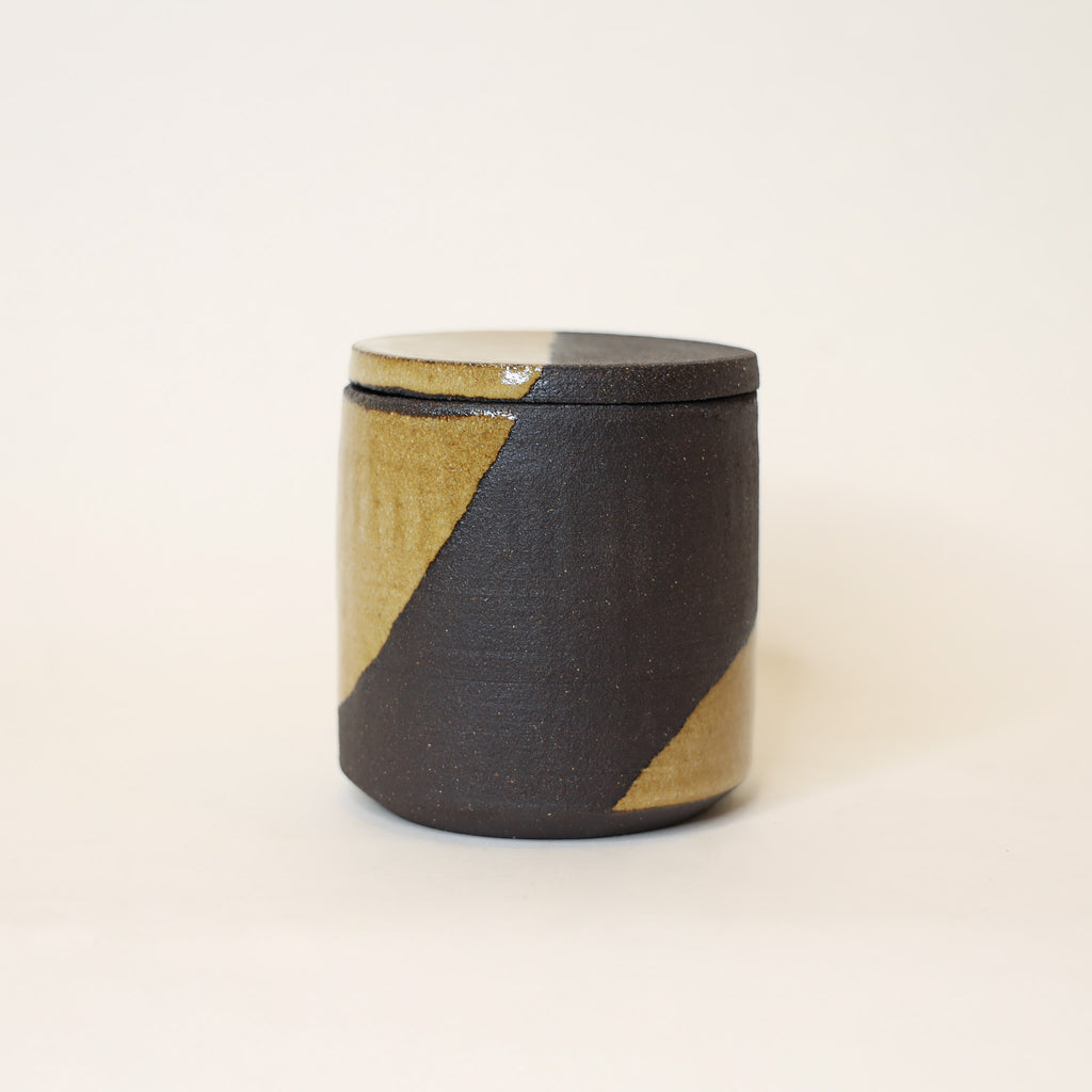 Ceramic container with black and beige design on a white background