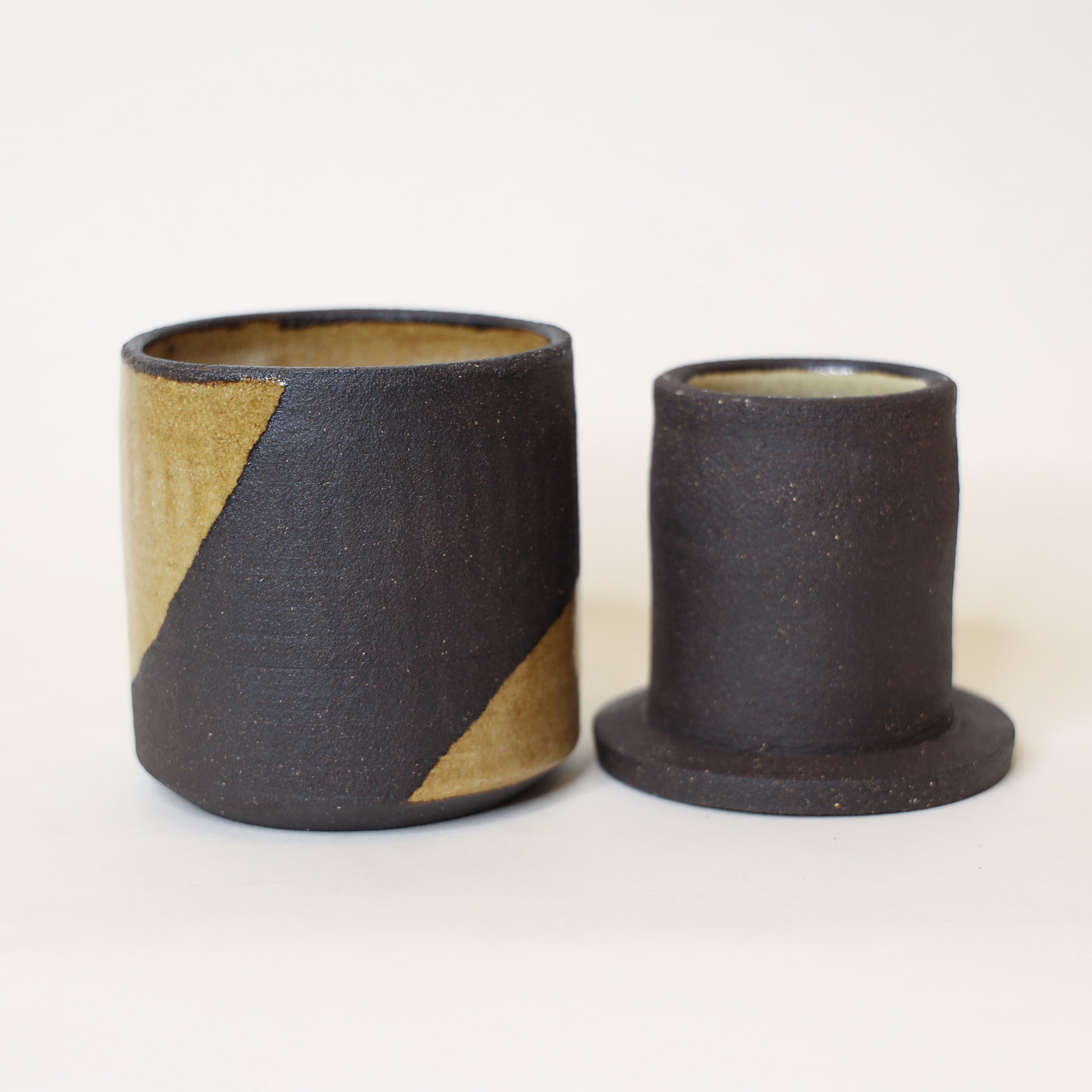 Two ceramic cups with a black and gold design on a white background