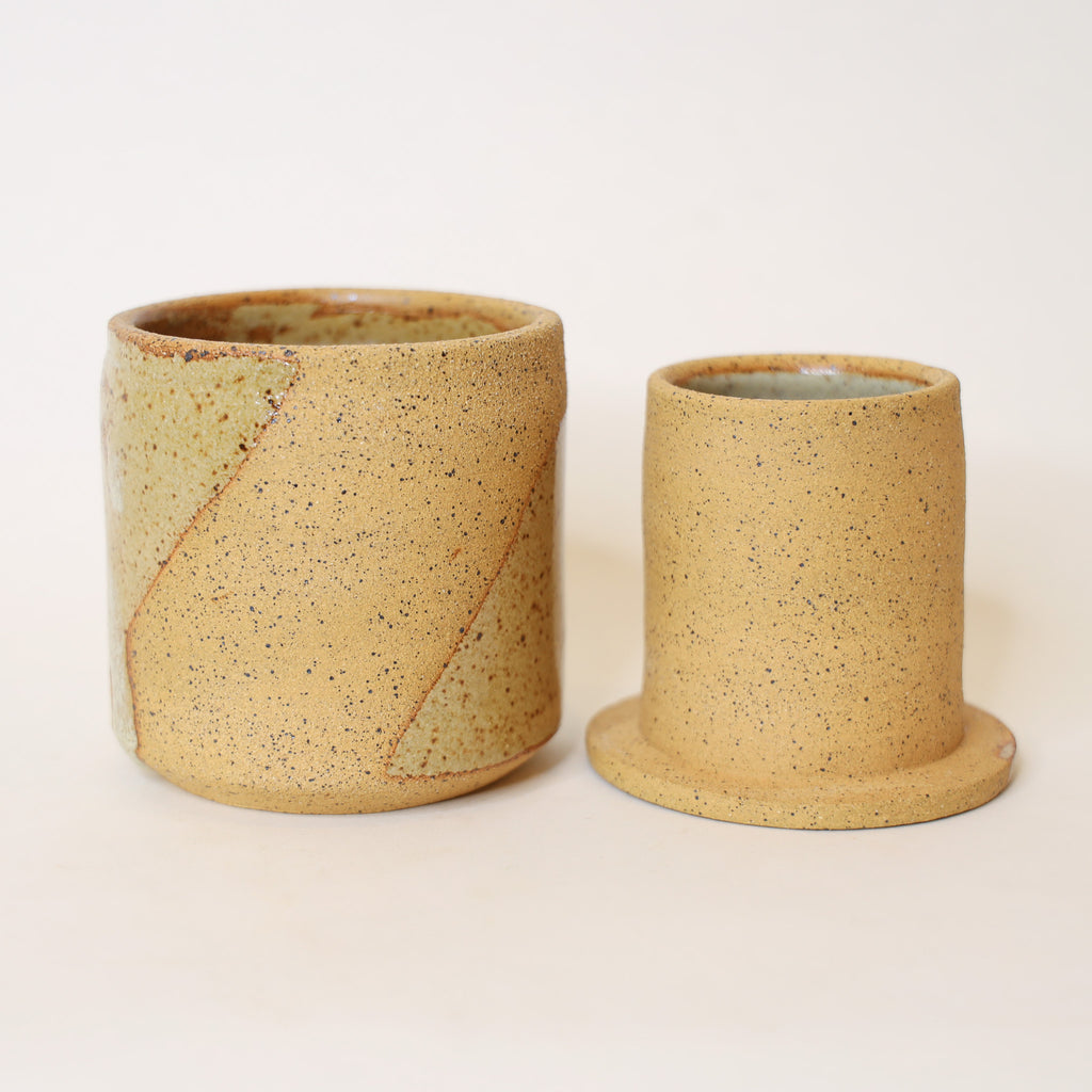 Two ceramic cups with a speckled texture on a light background