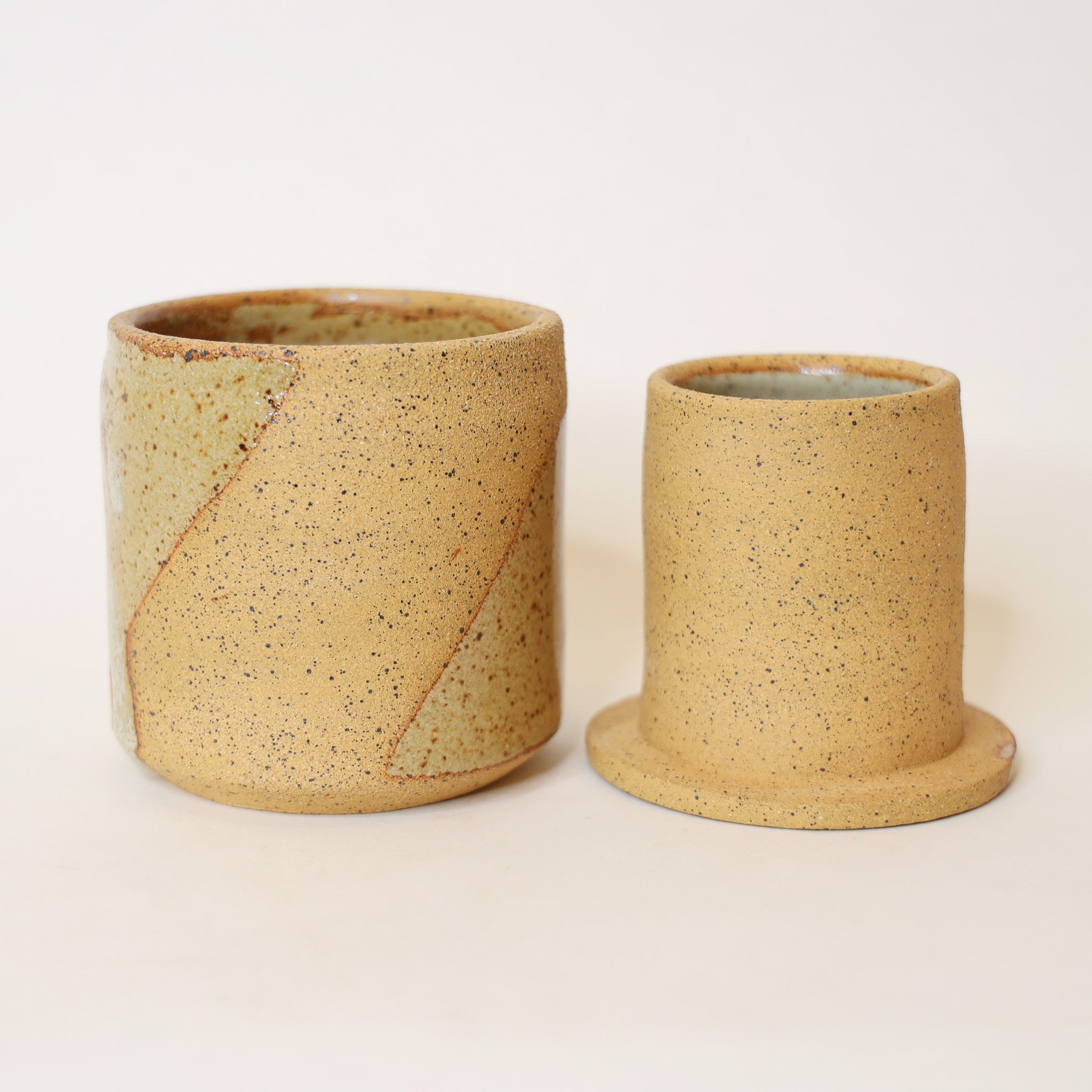 Two ceramic cups with a speckled texture on a light background