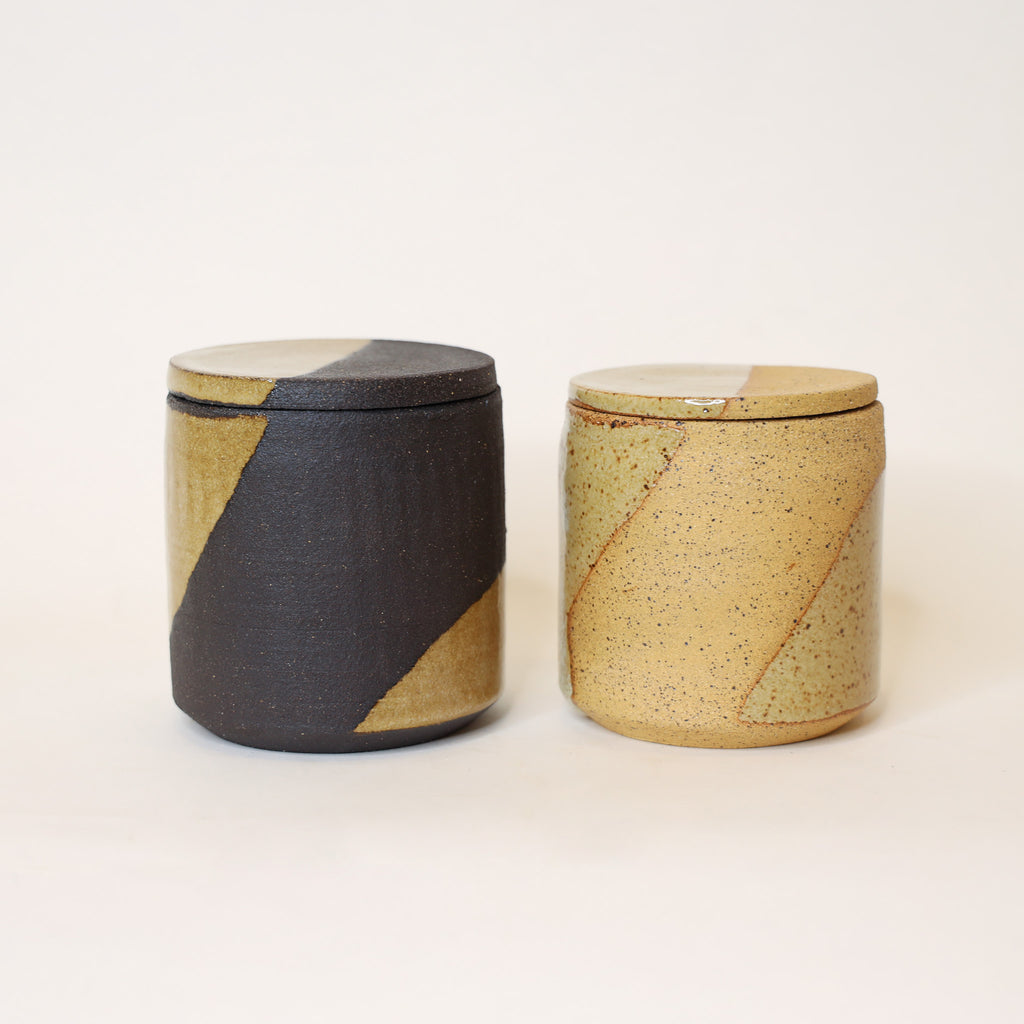 Two ceramic jars with striped patterns on a beige background