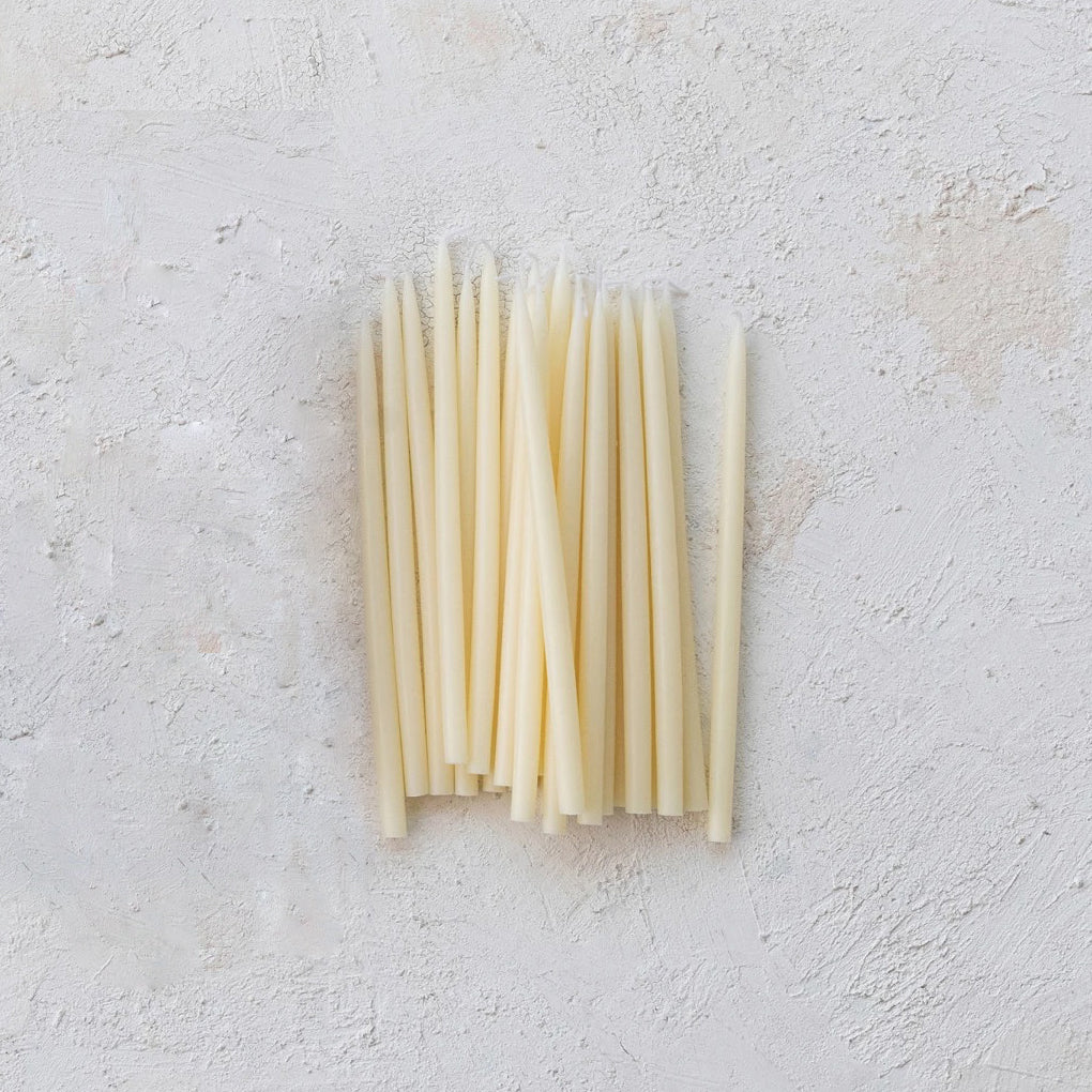 Set of white candles on a textured light gray surface
