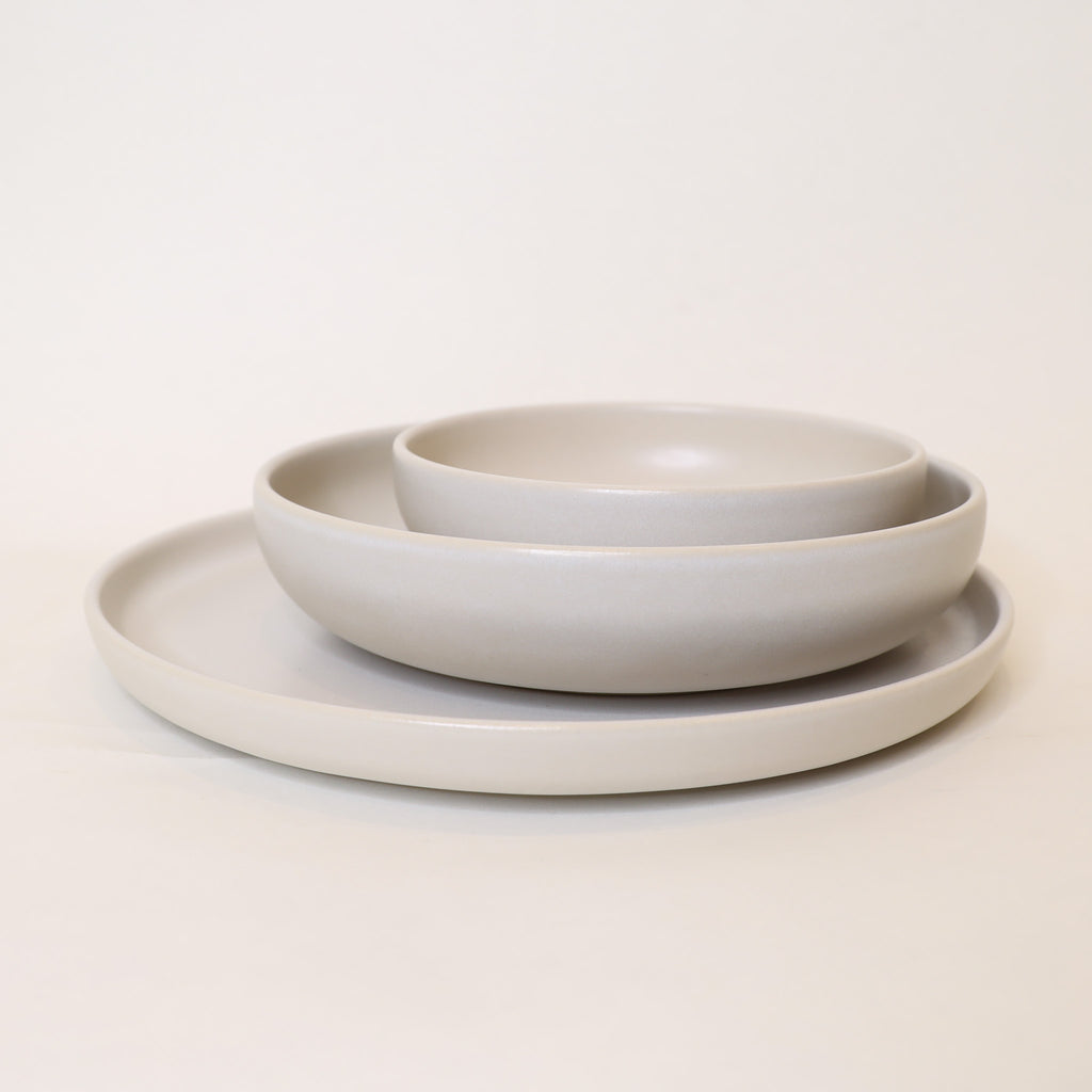 Set of three beige ceramic bowls on a light beige background