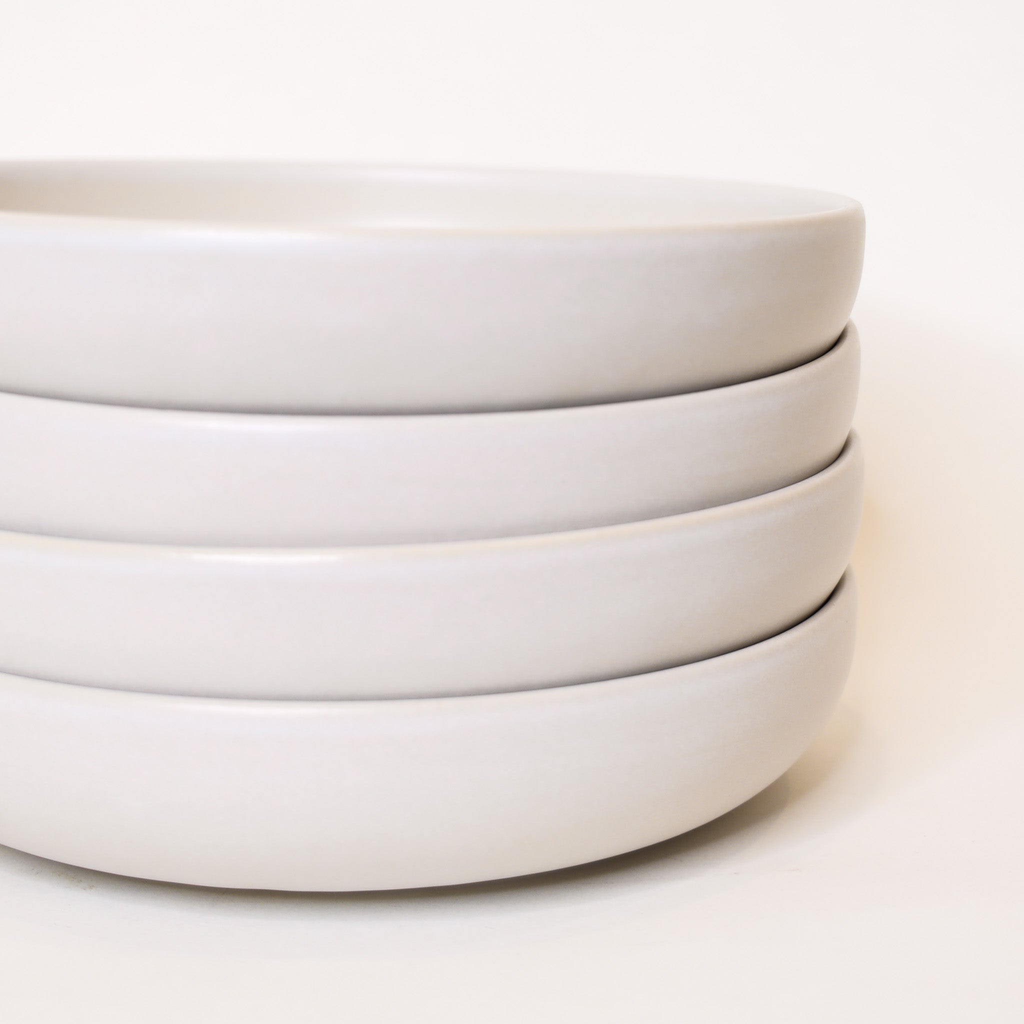Stack of white ceramic bowls on a light beige background