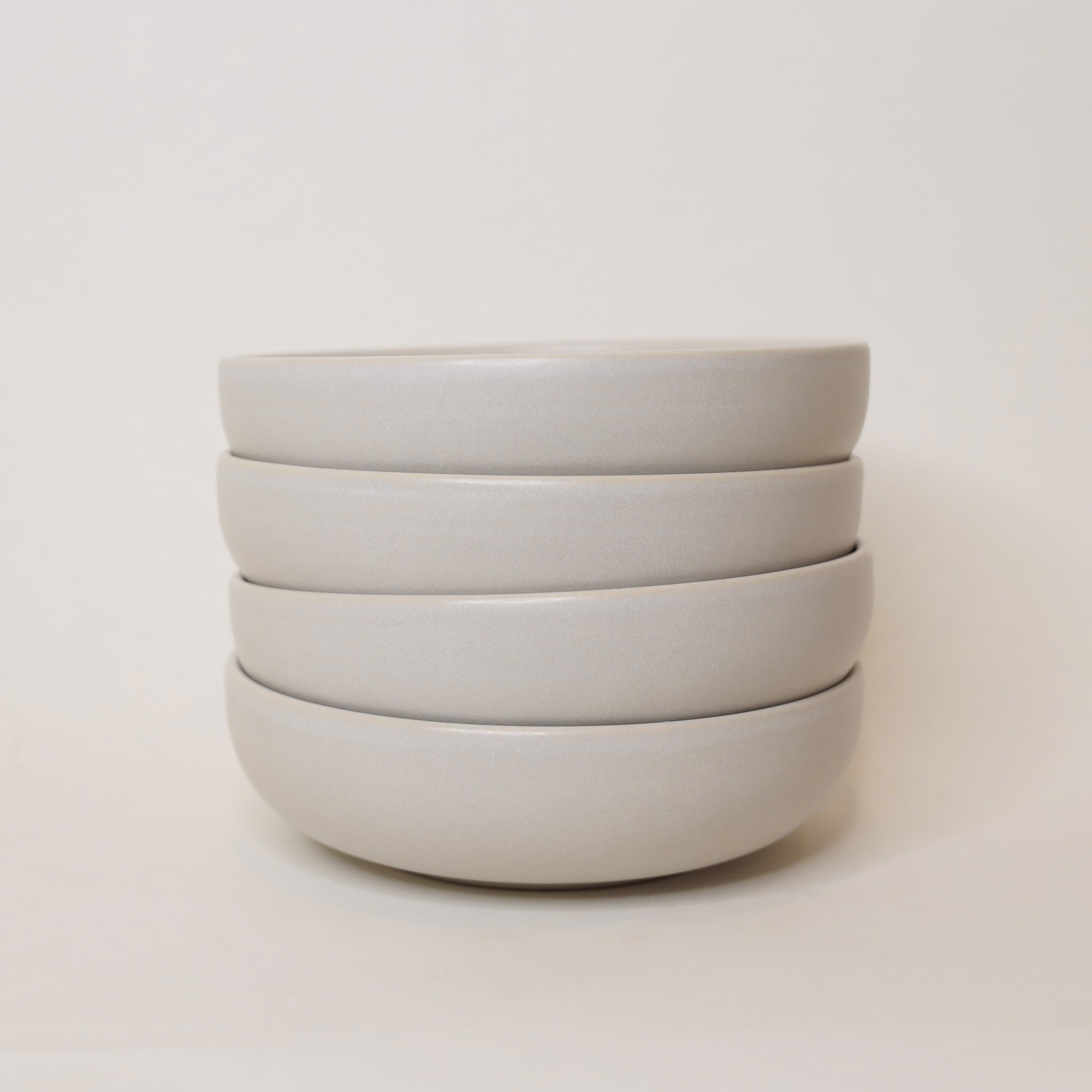Stack of white ceramic bowls on a light beige background