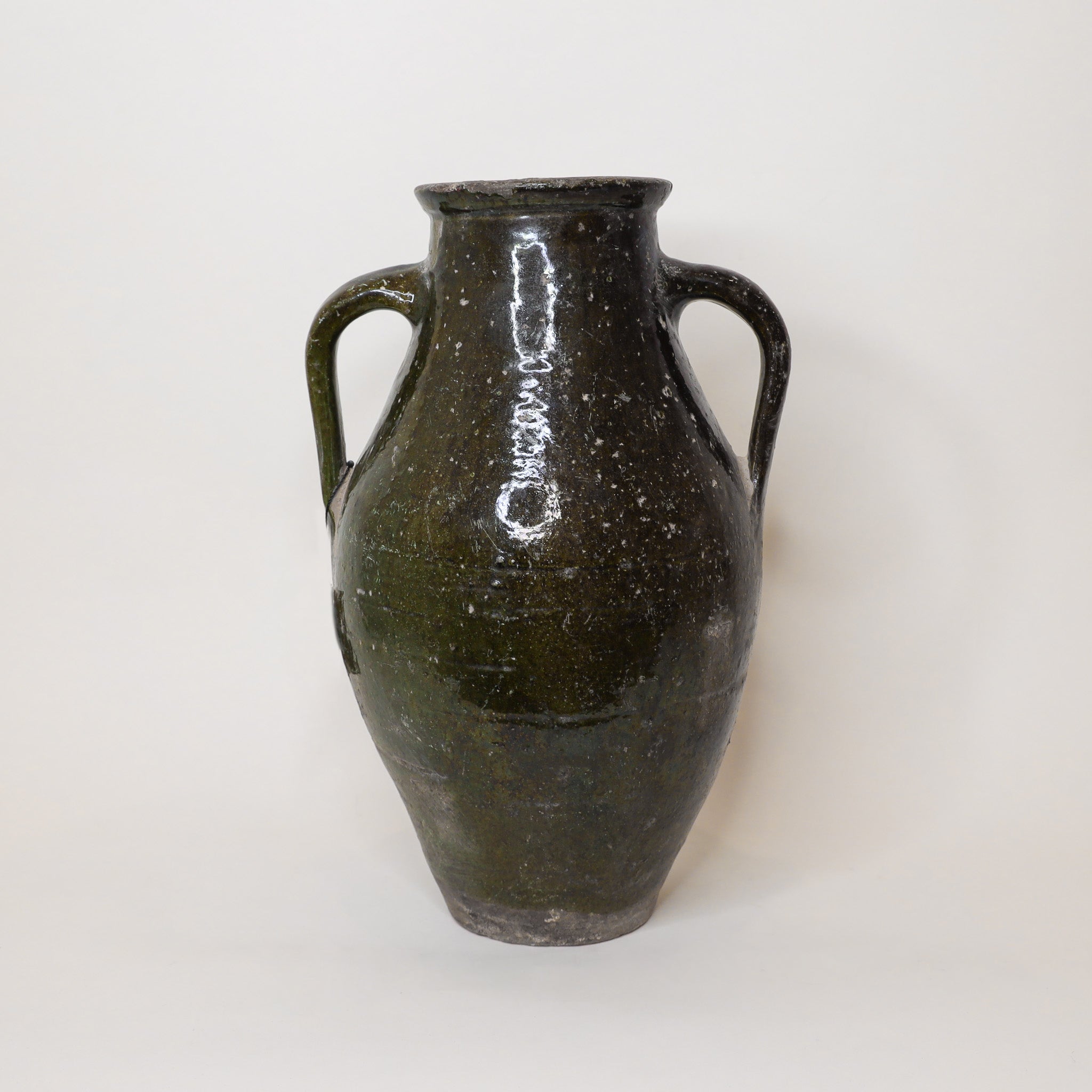 Dark green antiqued vase with two handles on a white background