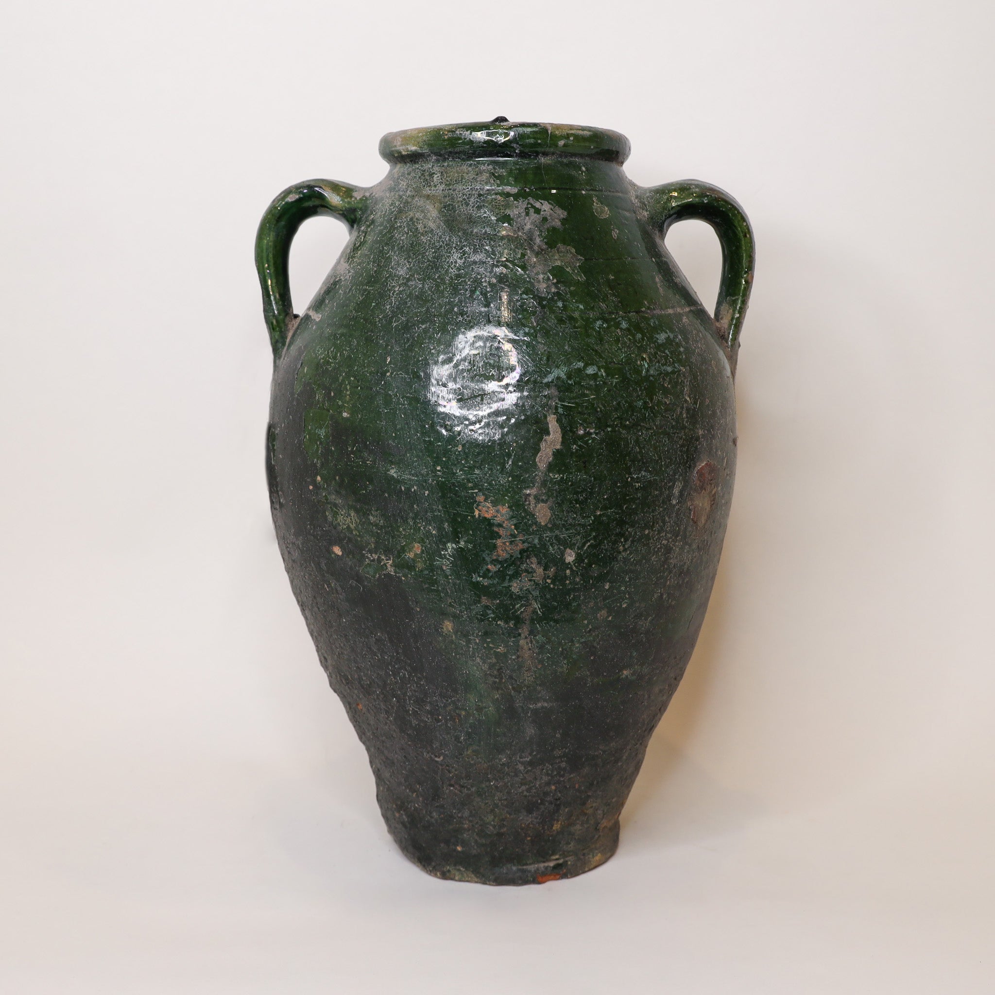 Green ceramic jar with two handles on a white background