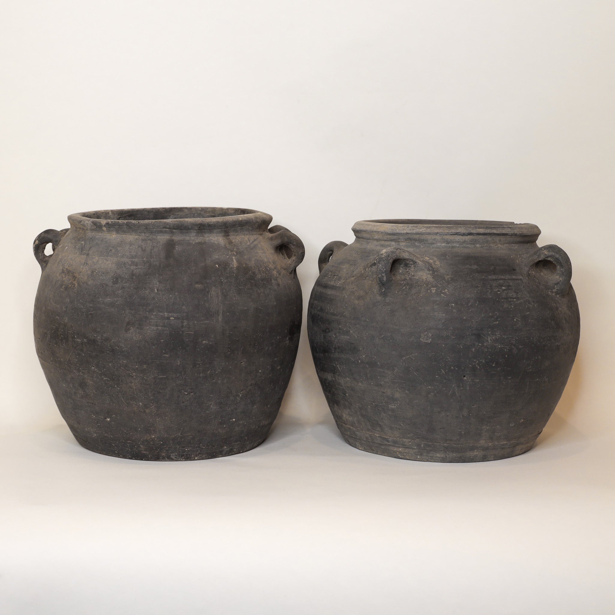 Two black earthenware pots on a white background